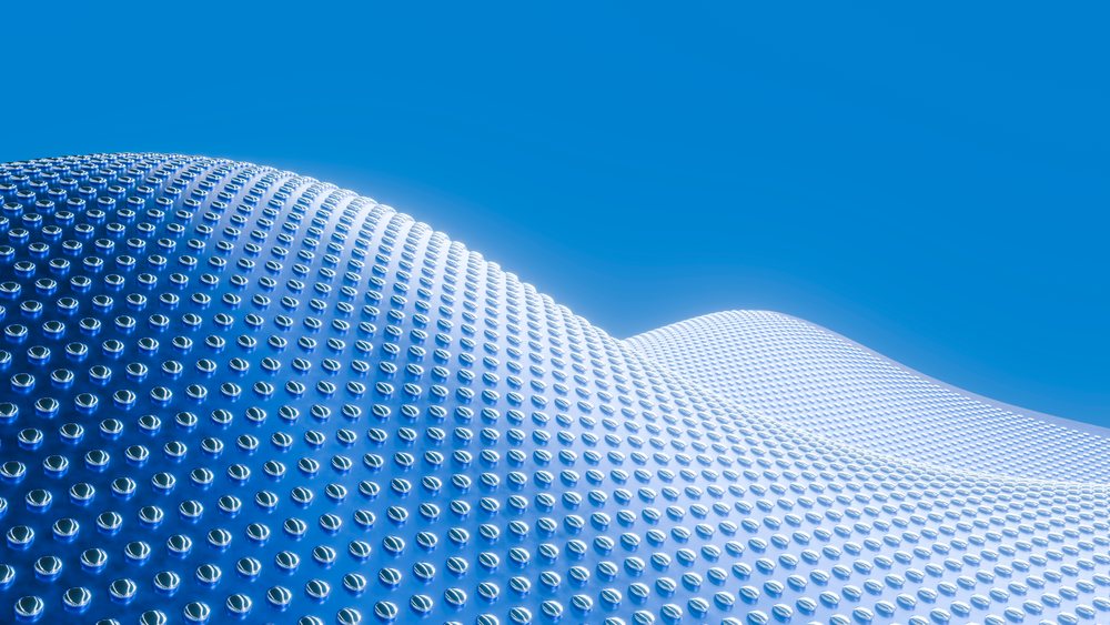 Curved reflective metal surface with round studs under blue sky