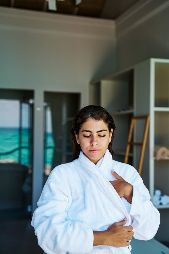 A woman relaxes in a white bathrobe inside a spa room