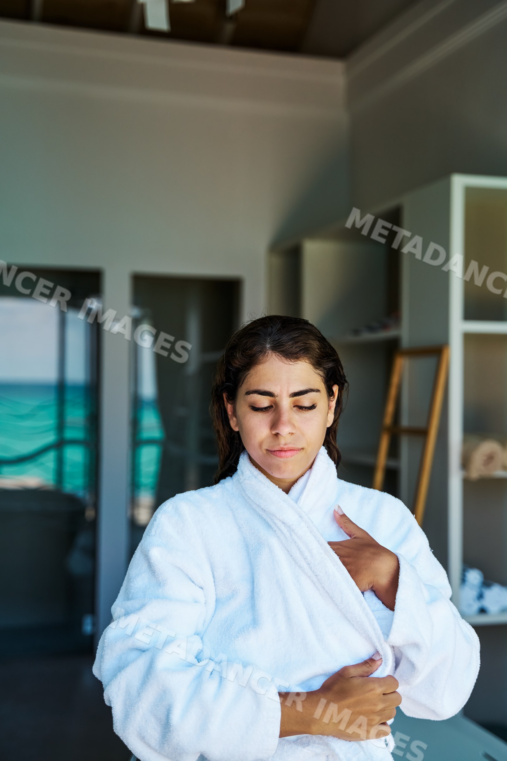 A woman relaxes in a white bathrobe inside a spa room