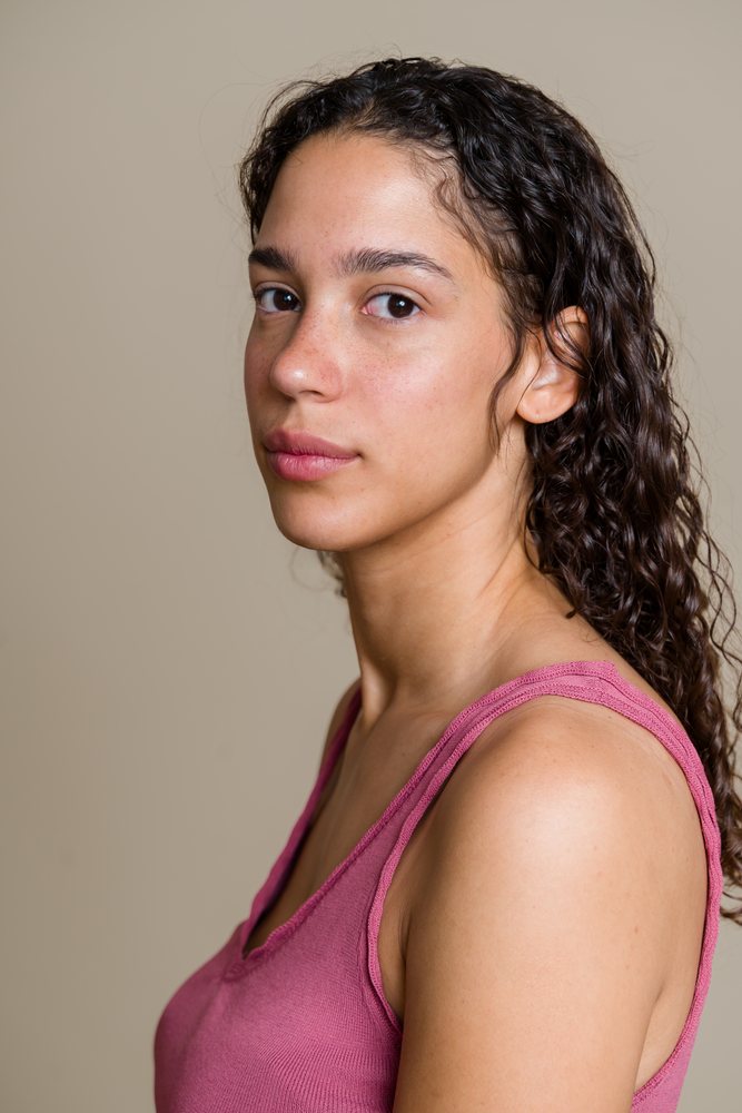 Portrait of a Hispanic woman with curly hair in pink tank top