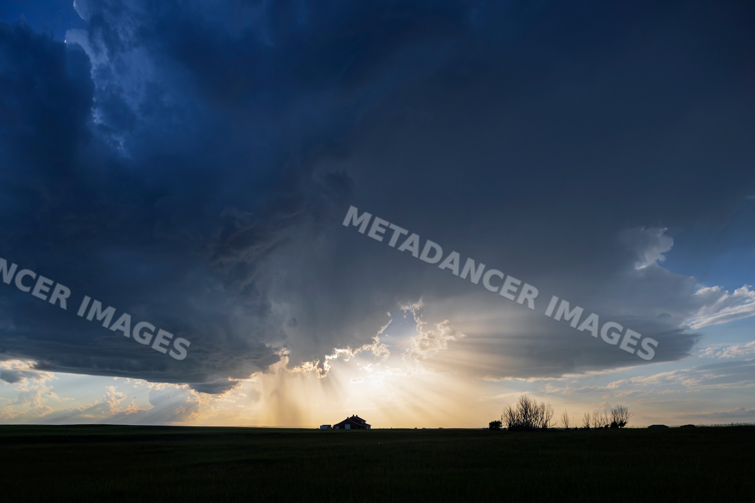 Farm house with storm clouds and sun rays at Sunset in alberta, Canada