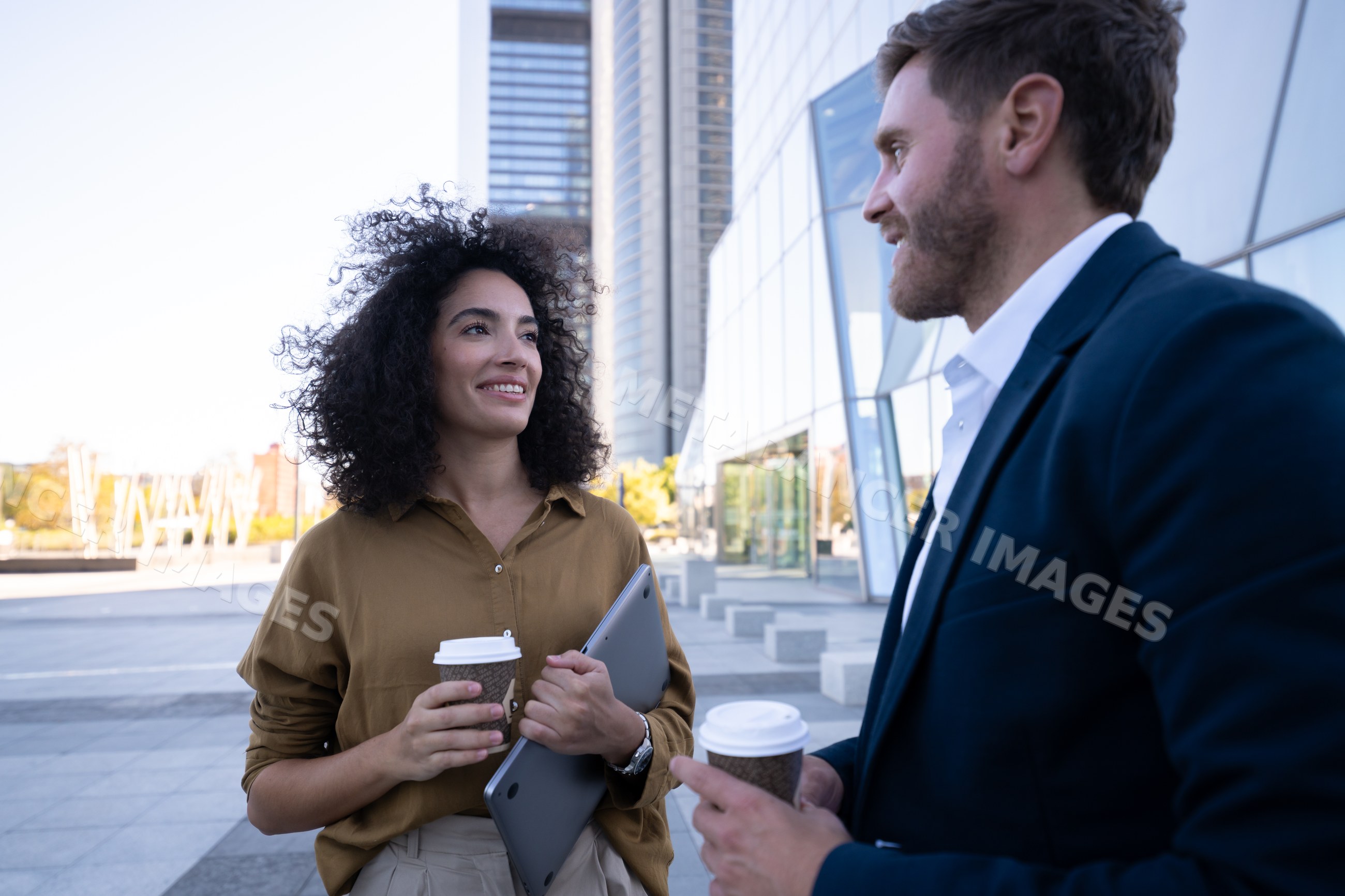 Two businesspeople conversing outdoors at modern office building