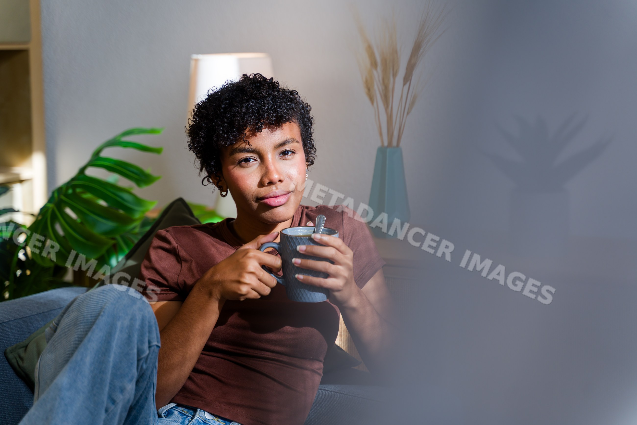 African American woman relaxing on sofa holding a cup indoors