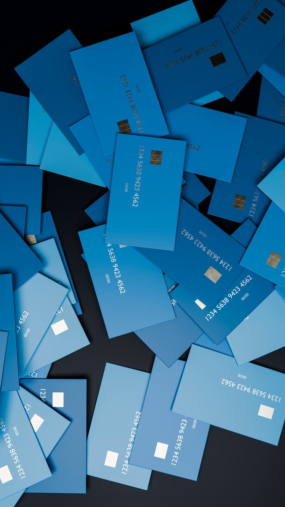 Scattered blue credit cards with payment chips on a black surface