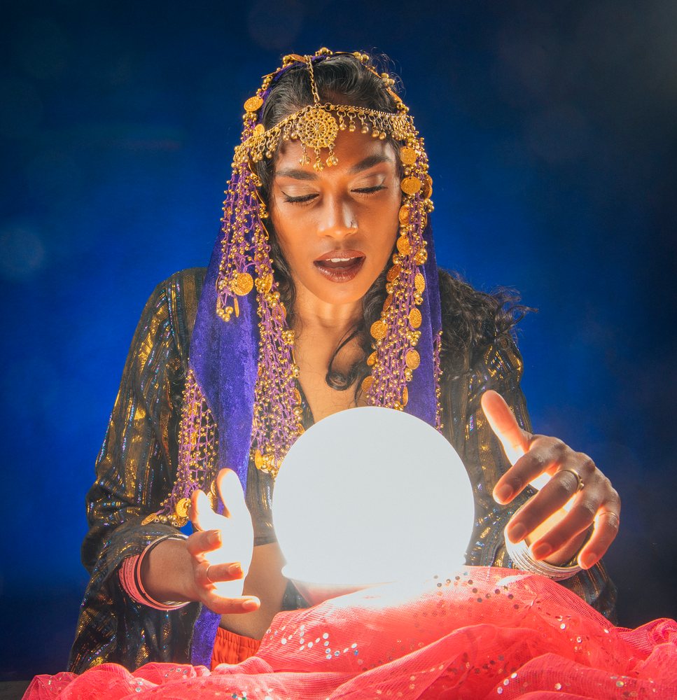 A fortune teller gazes into a glowing crystal ball in a mystic setting