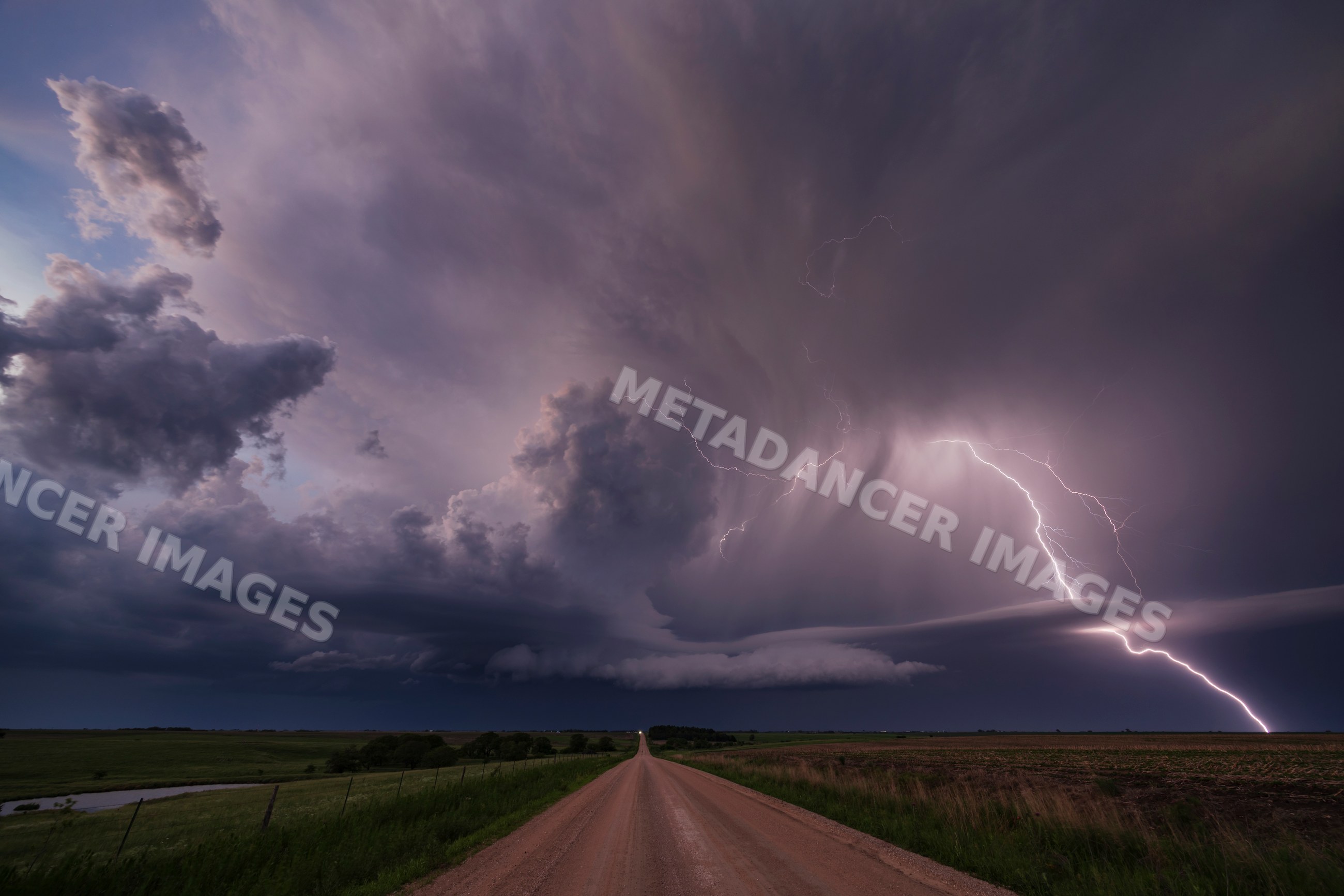 Supercell storm with Lightning over rural road at Sunset in nebraska