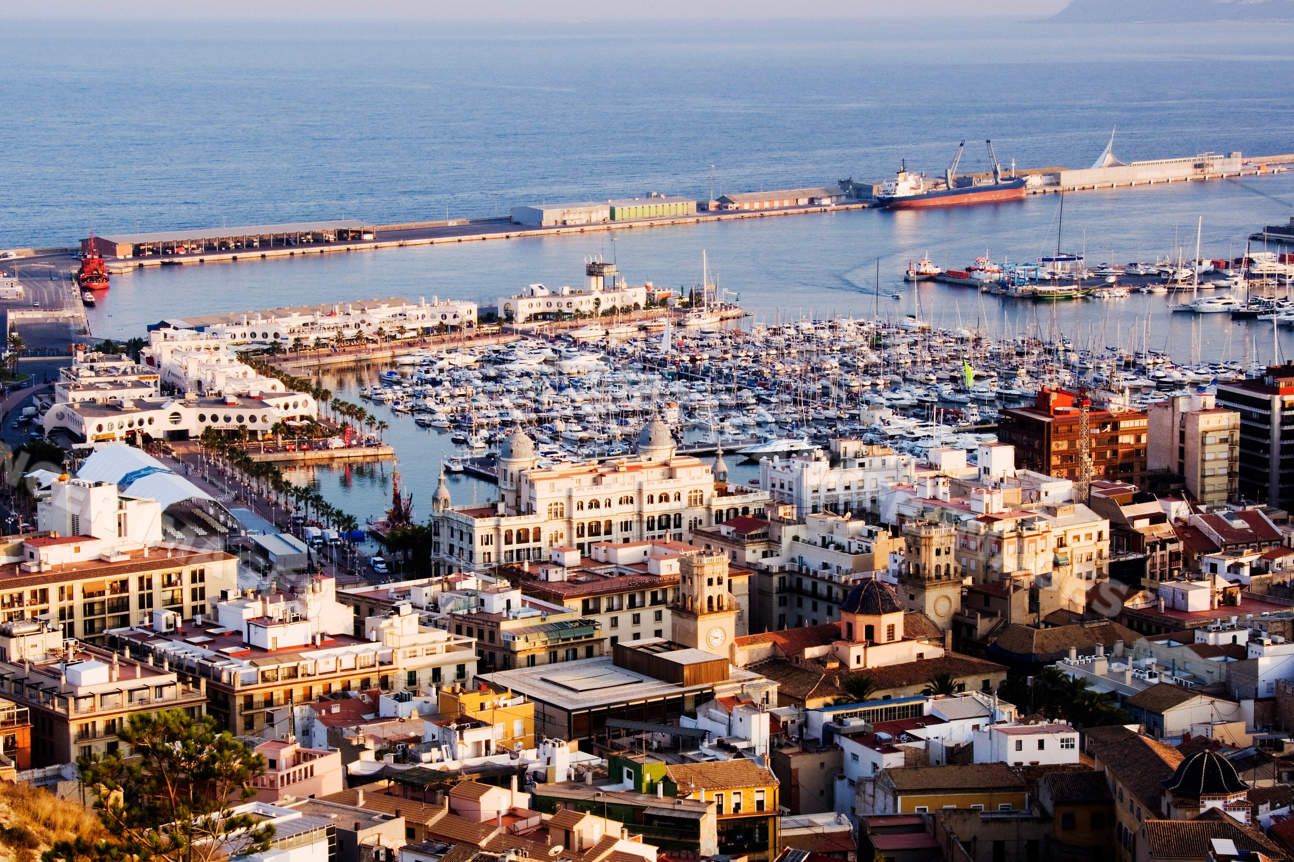 Marina harbor with yachts and urban buildings at sunset Spain