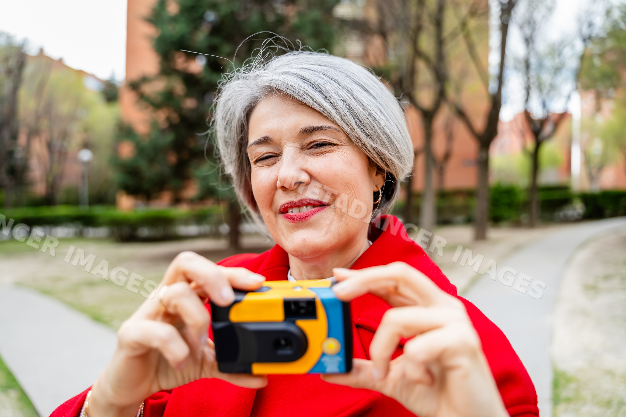 White woman taking photo with camera outdoors in a park