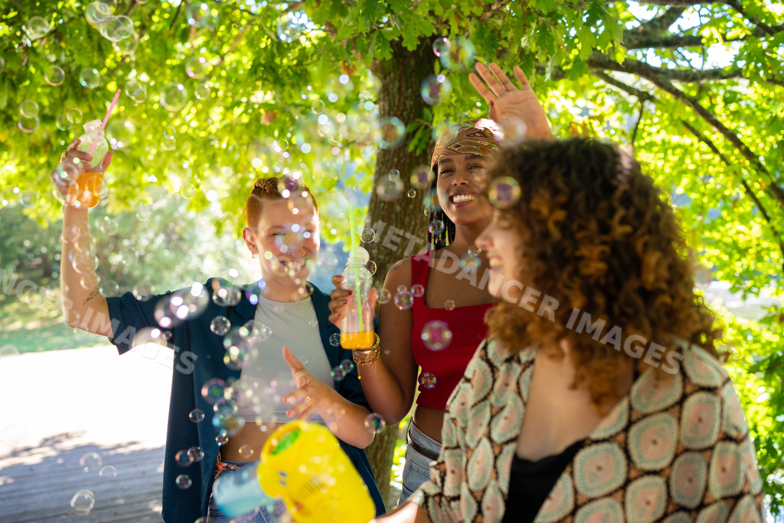 Friends enjoying bubbles outdoors in sunny greenery