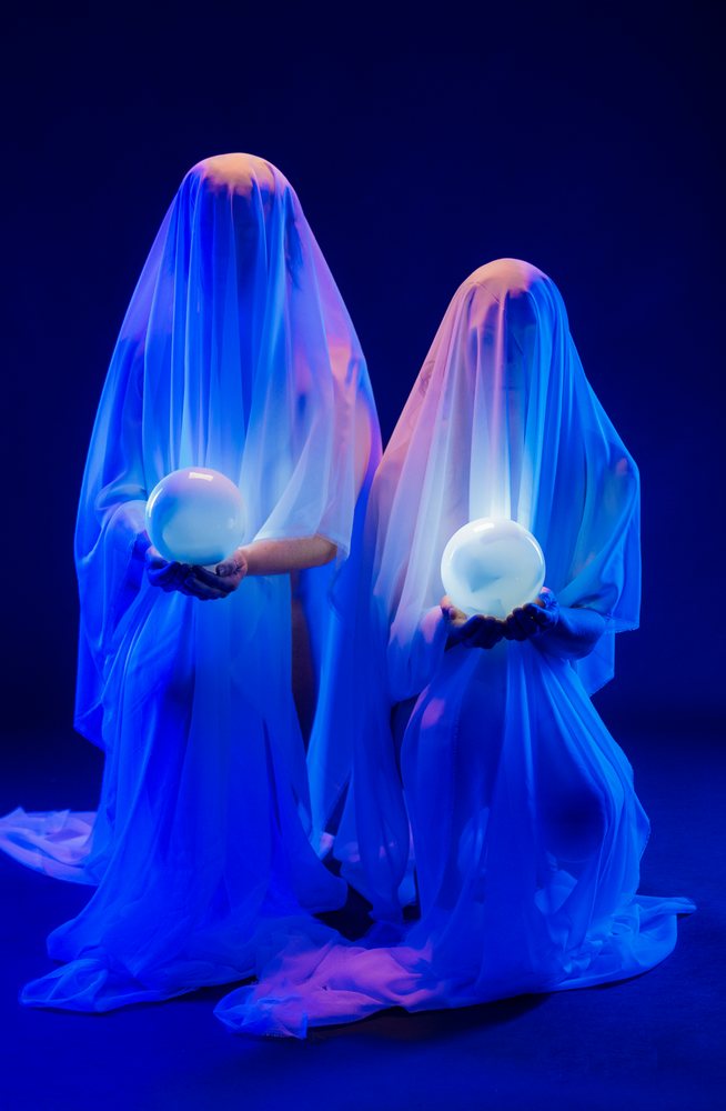 Two ghost figures holding glowing orbs under blue lighting
