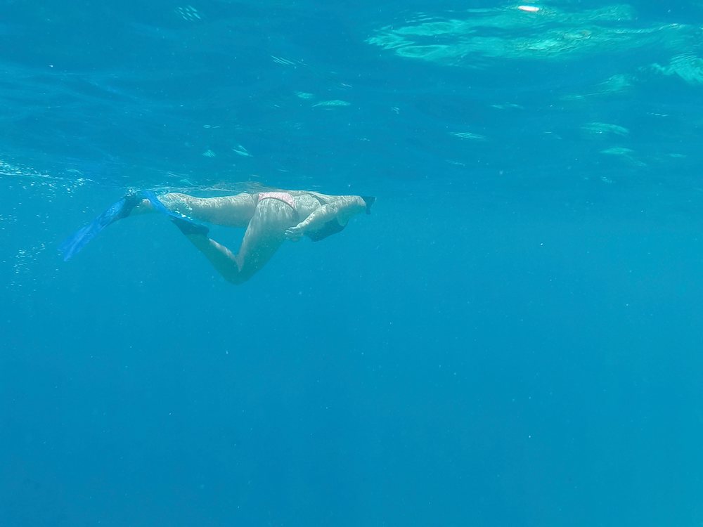 A woman snorkeling underwater in the blue sea of Maldives
