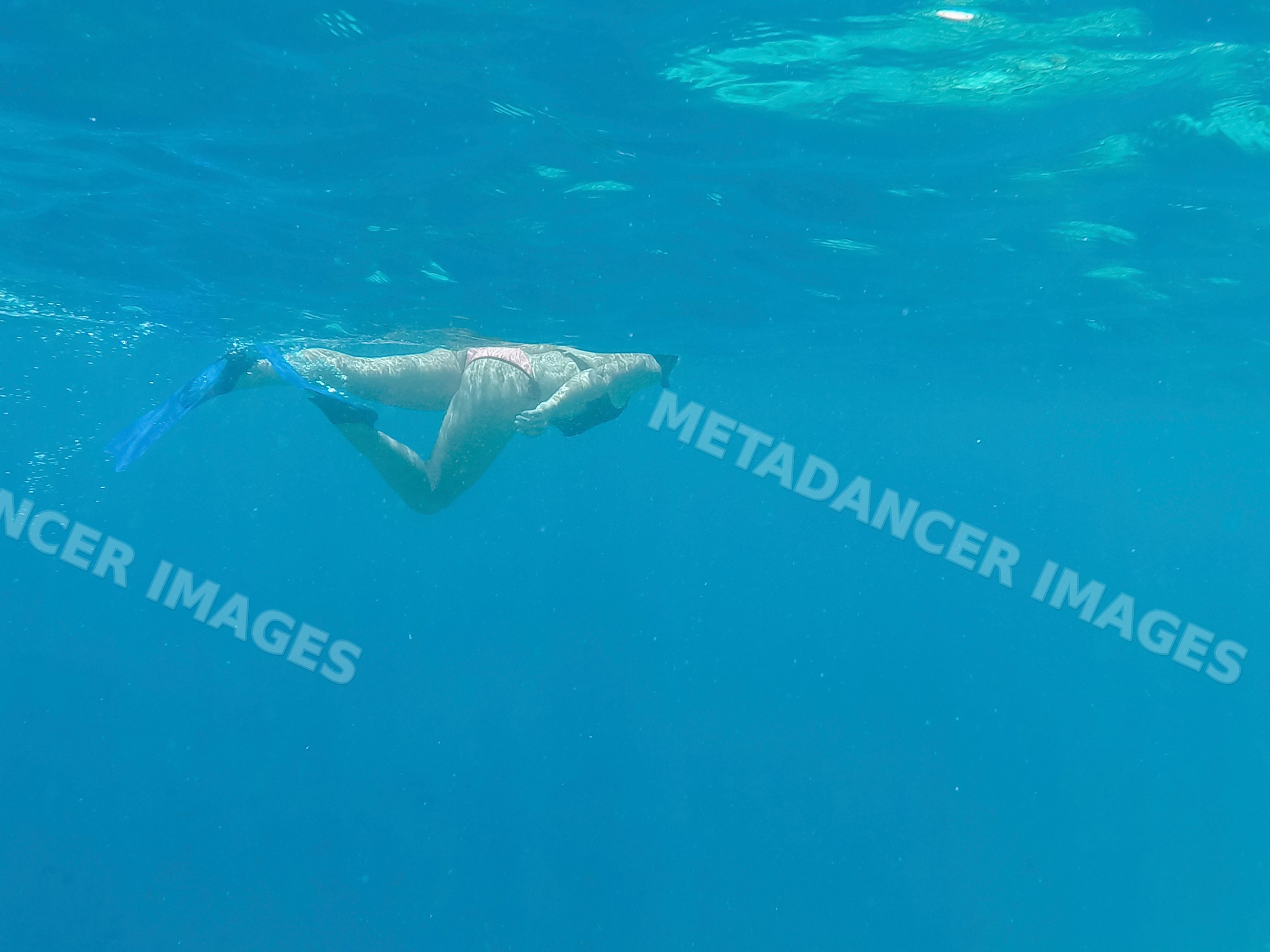 A woman snorkeling underwater in the blue sea of Maldives