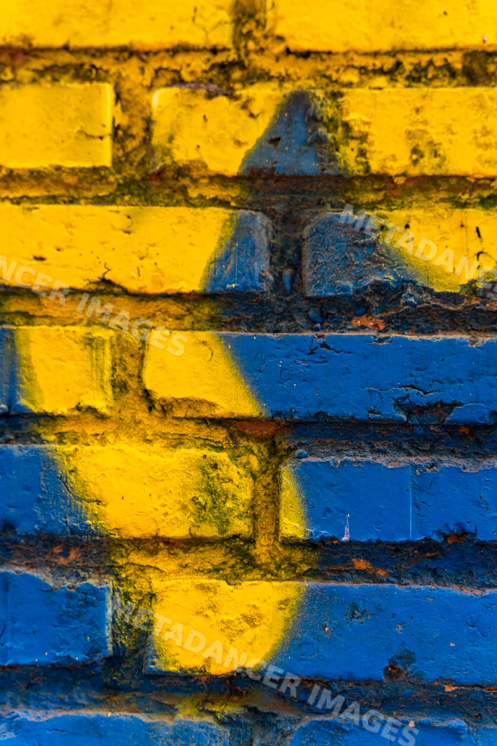 Close-up of a painted blue and yellow brick wall
