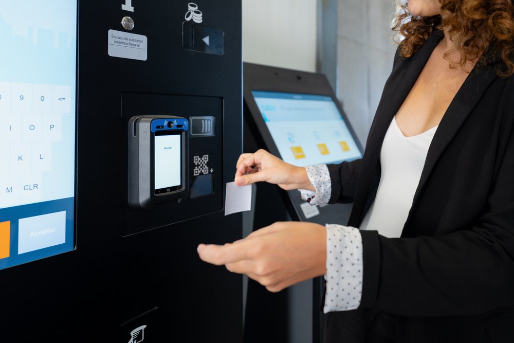 White woman collecting ticket from public transport ticket machine