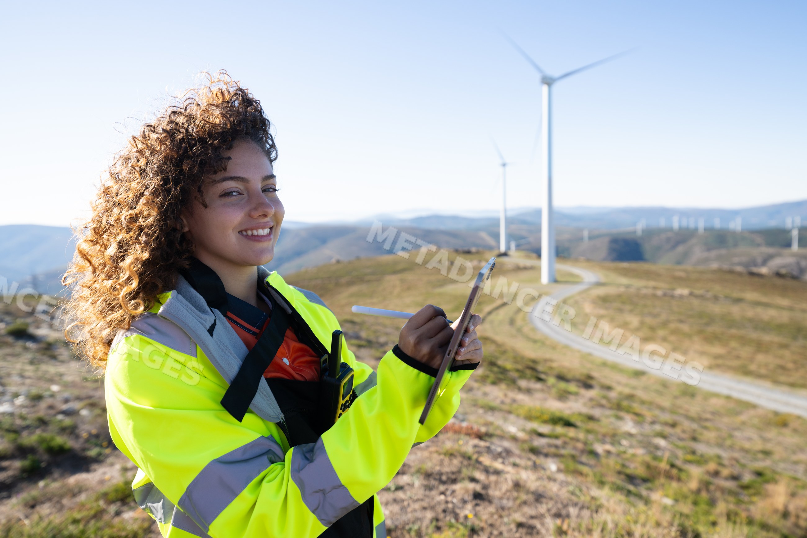 White woman using tablet at wind farm with wind turbines in Galicia