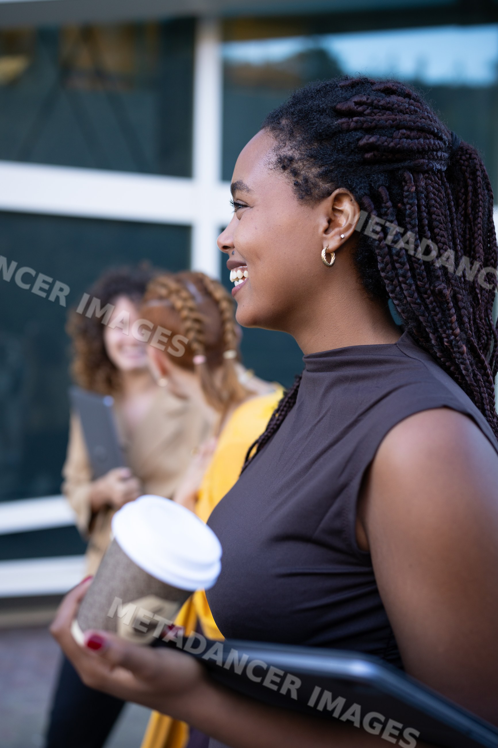 African American and white woman holding coffee cup and laptop