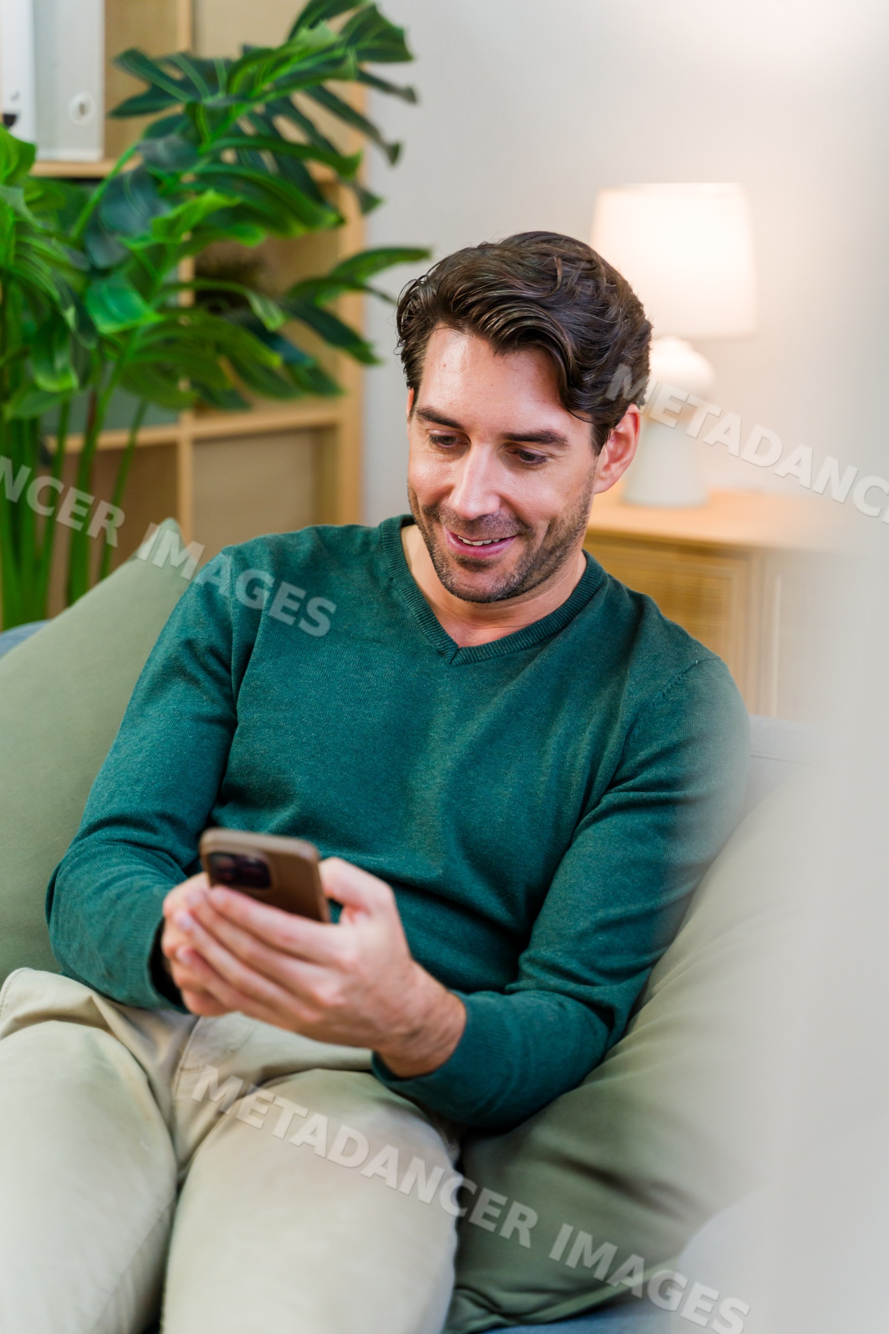 White man using smartphone on sofa in modern living room