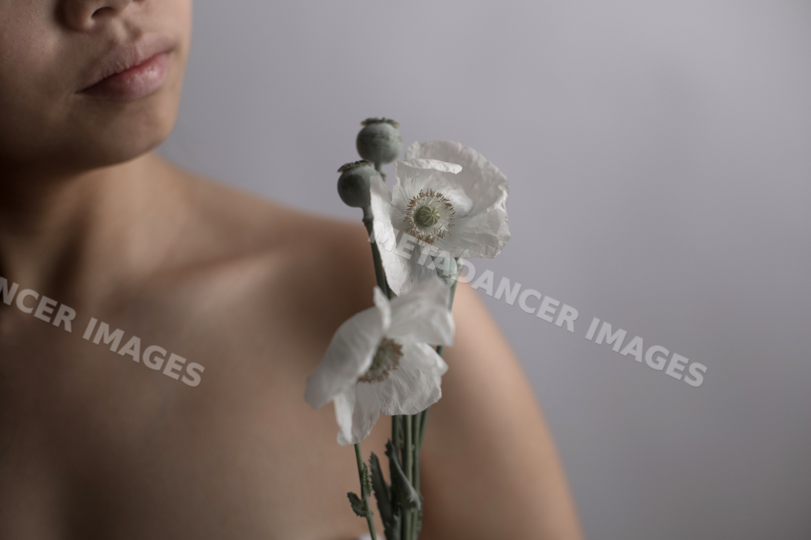 Southeast Asian woman holding white poppy flowers in a serene portrait