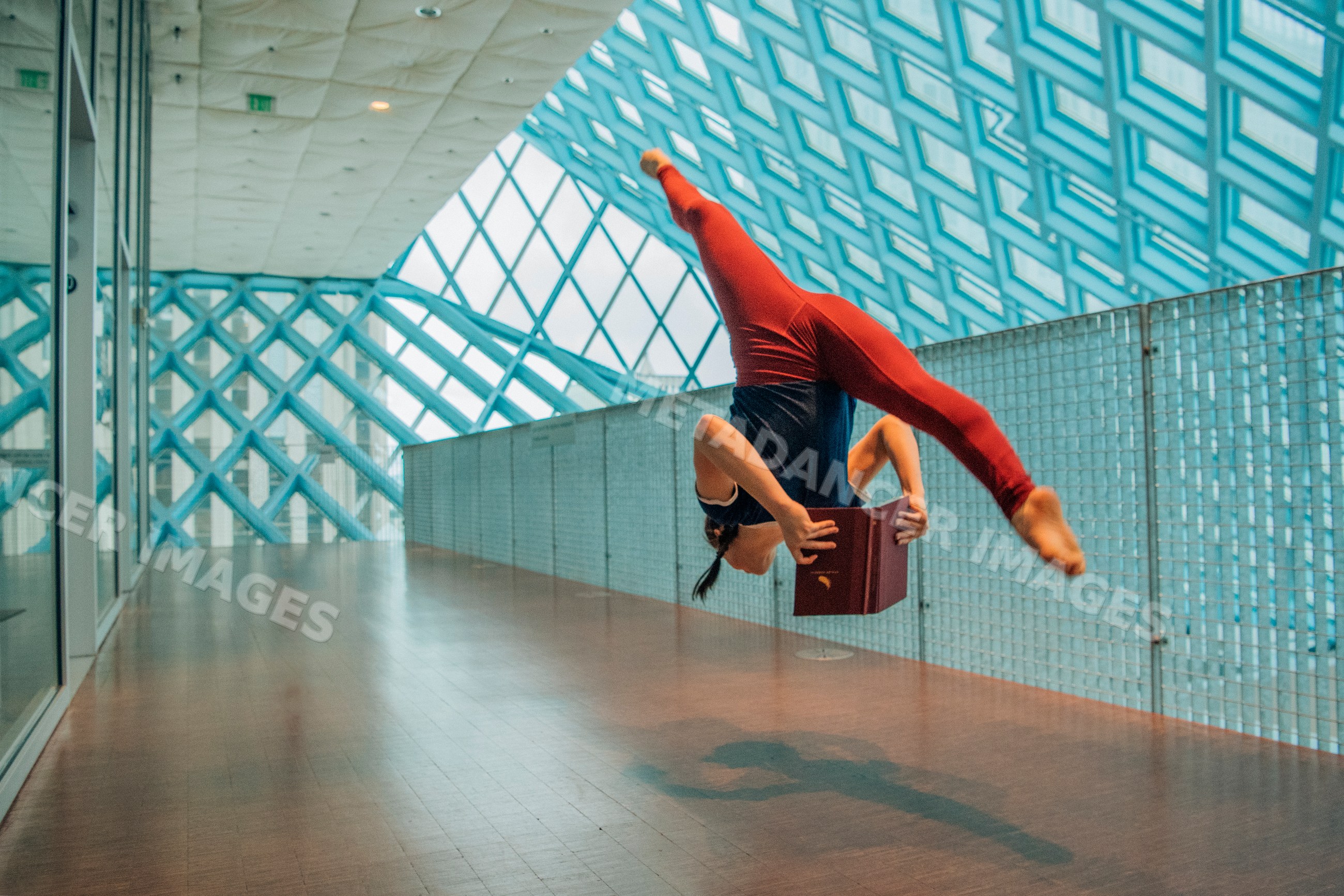Woman jumping and reading a book in a library