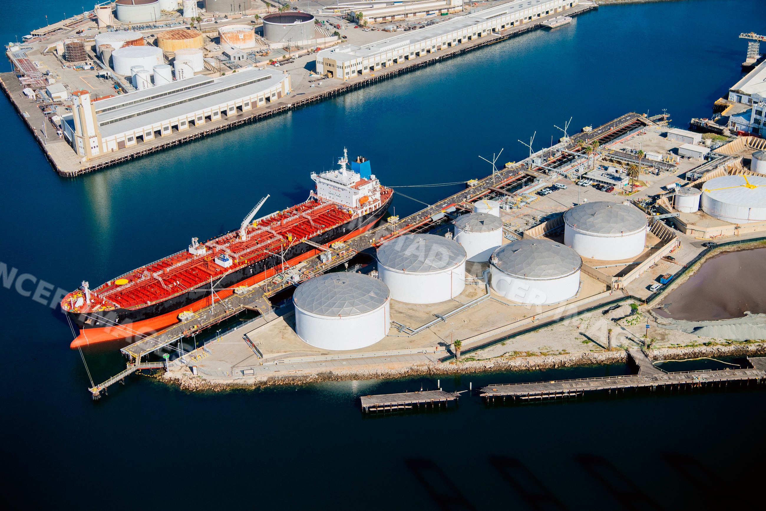 Oil tanker docked at industrial storage tanks in a beach
