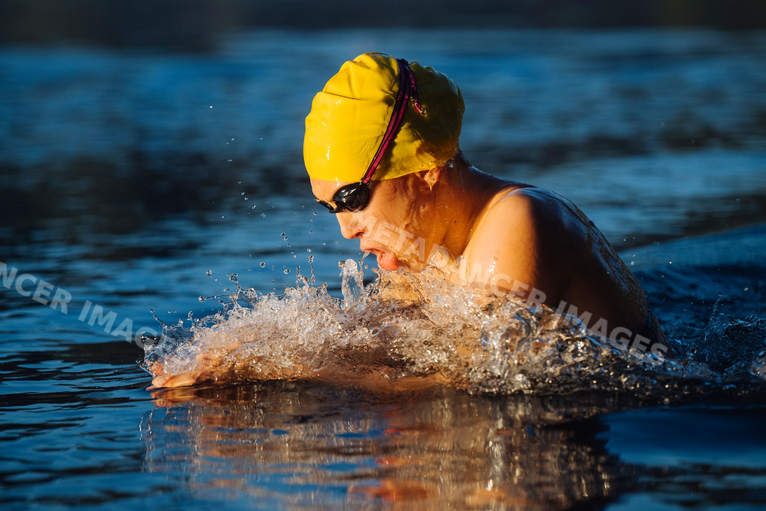 White swimmer performing breaststroke in open water with yellow cap