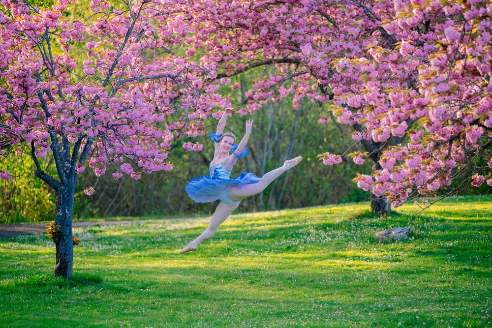 A dancer jumps gracefully beneath cherry