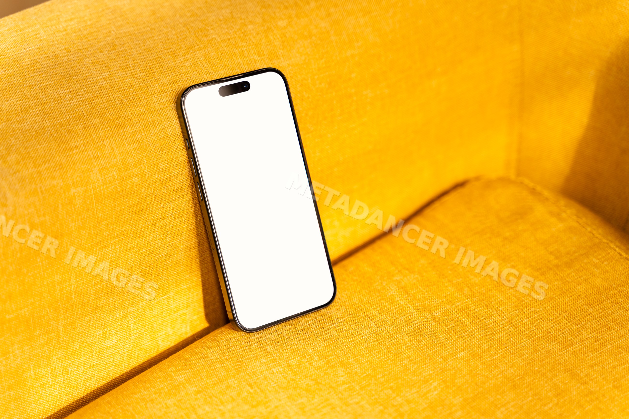 Black smartphone with blank screen on yellow sofa