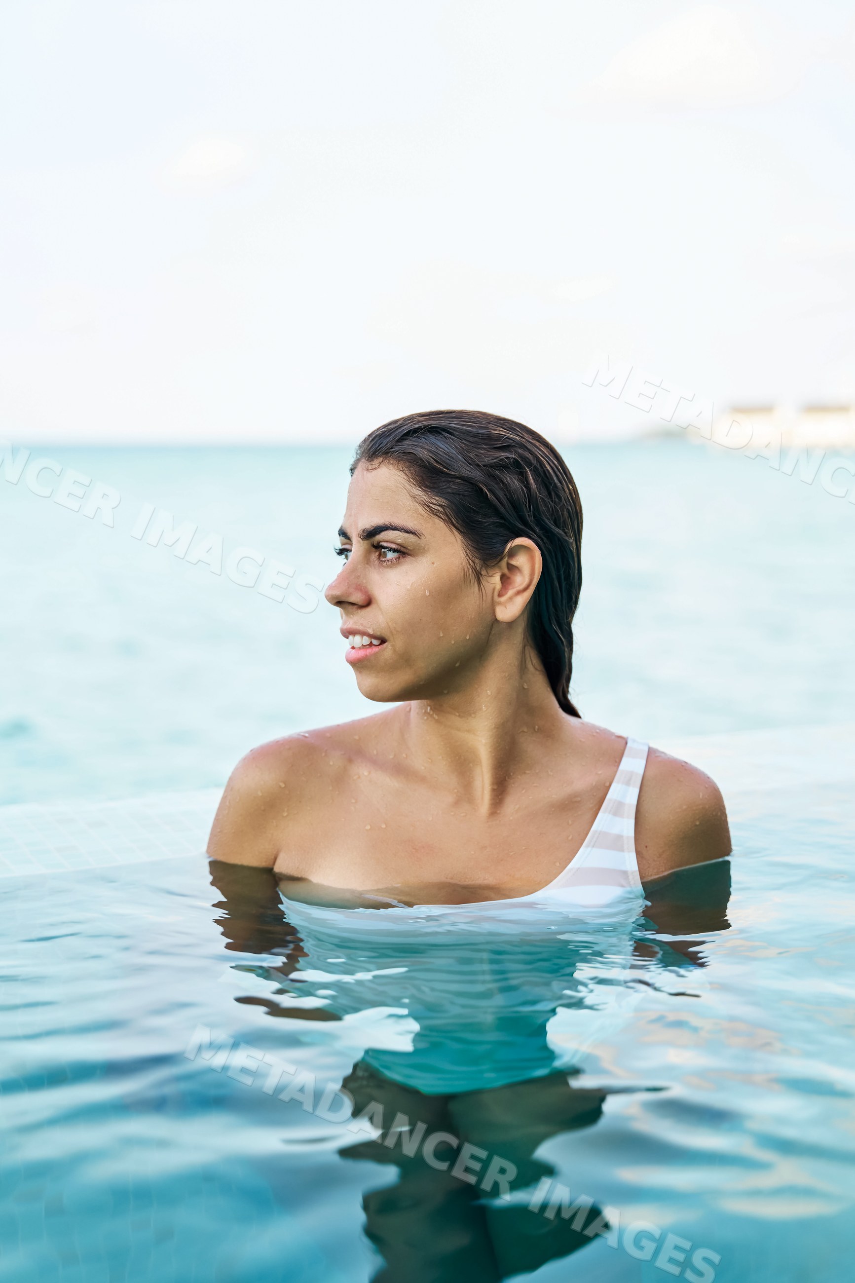 A young white woman enjoys swimming and relaxing in a pool