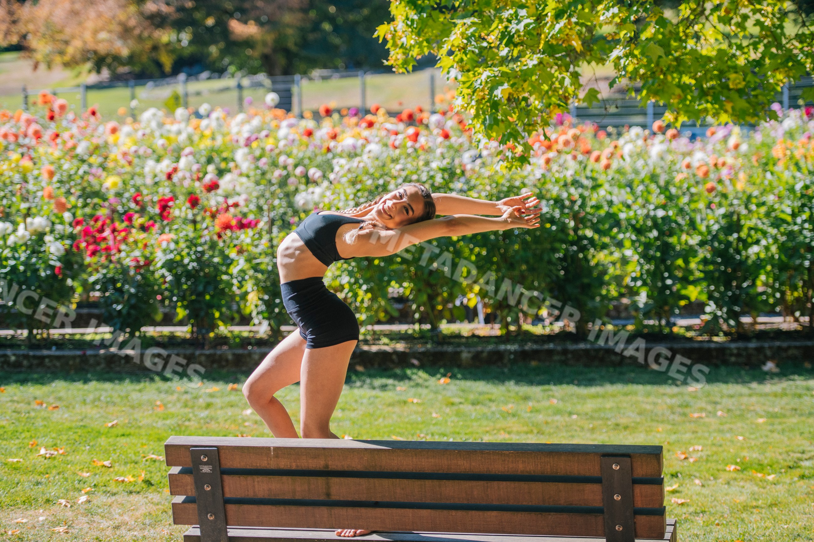 White woman contortionist stretching and posing on bench outdoors