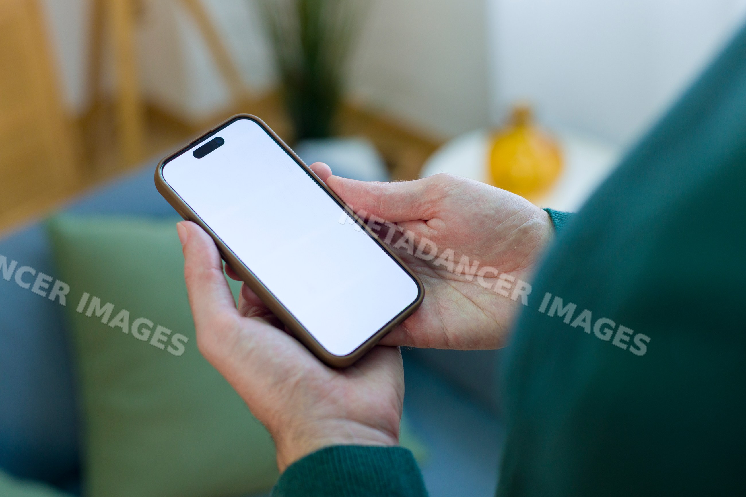 Hands holding smartphone with blank screen indoors