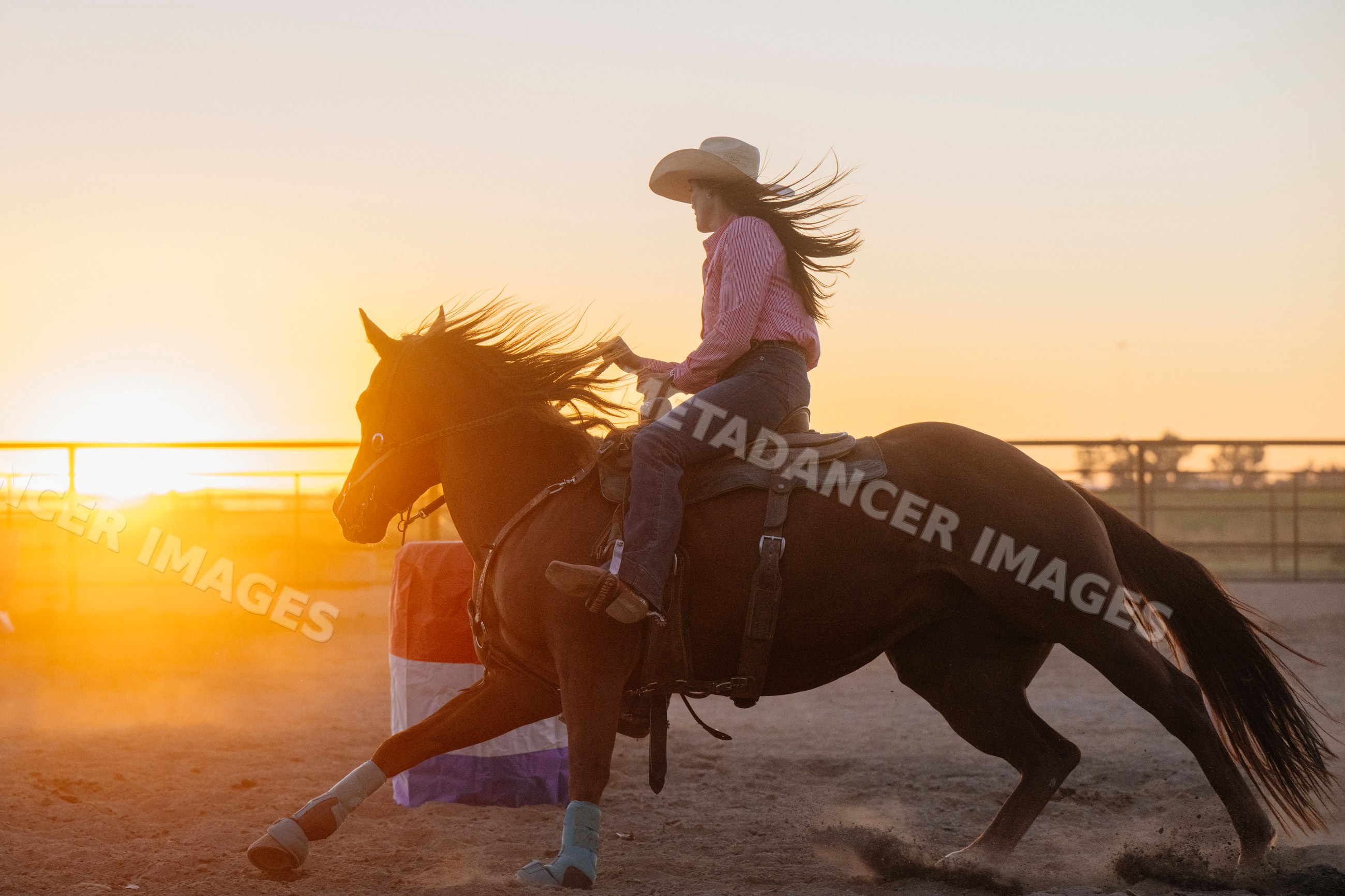 White woman riding horse at sunset in outdoor arena