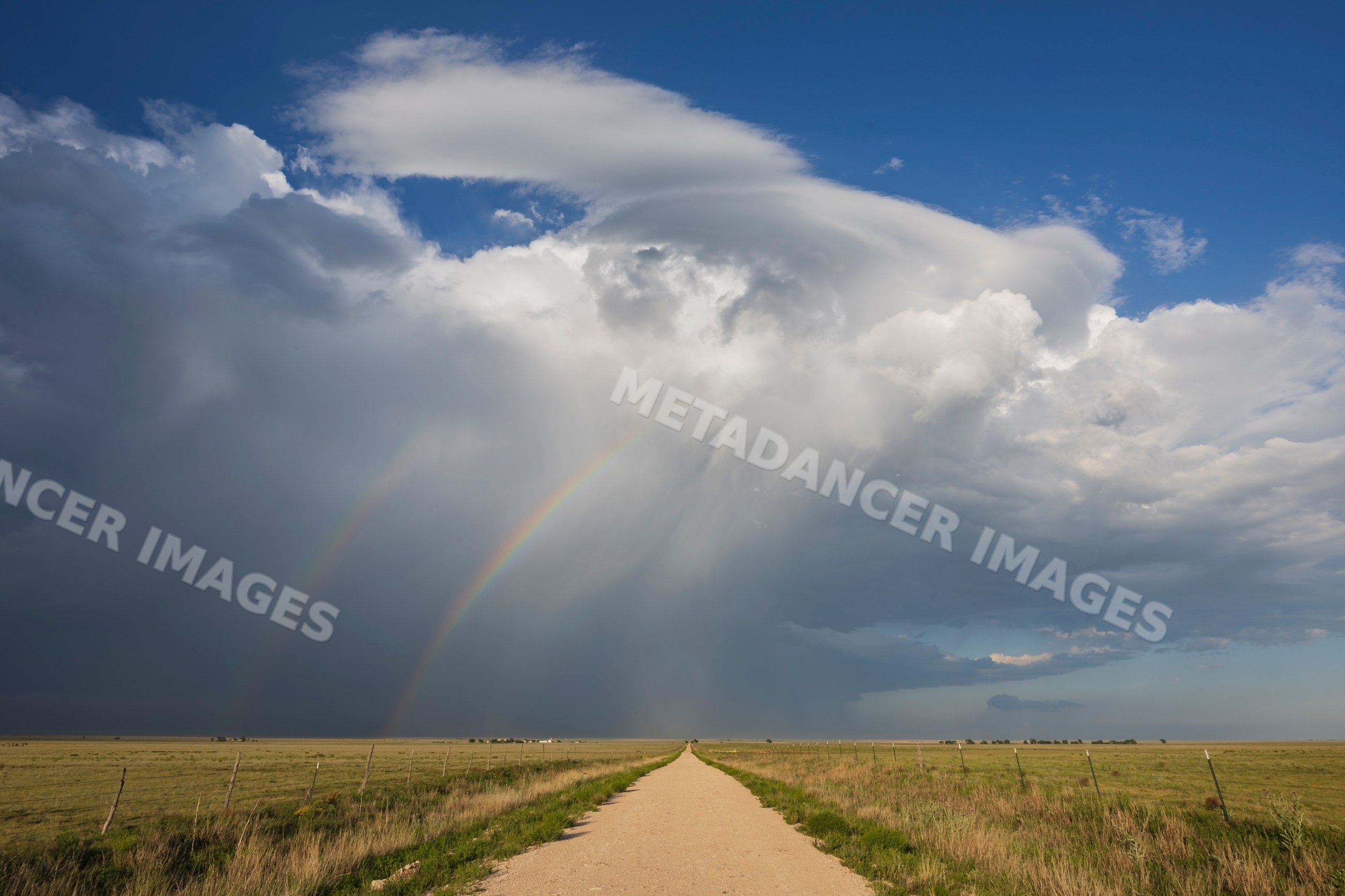 Supercell storm with Double Rainbow over grassland