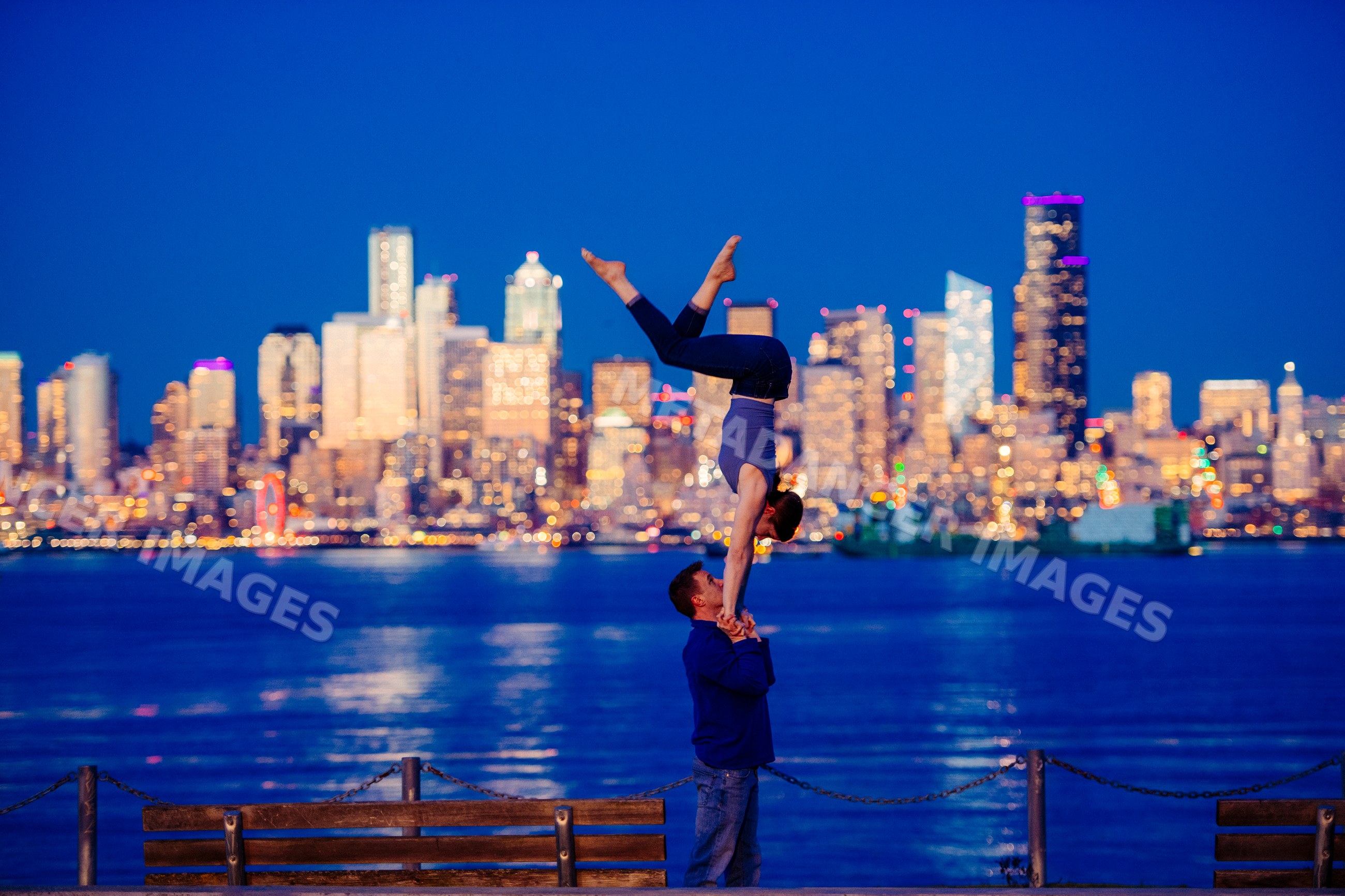 Partner acrobatics handstand yoga pose by Seattle waterfront at night