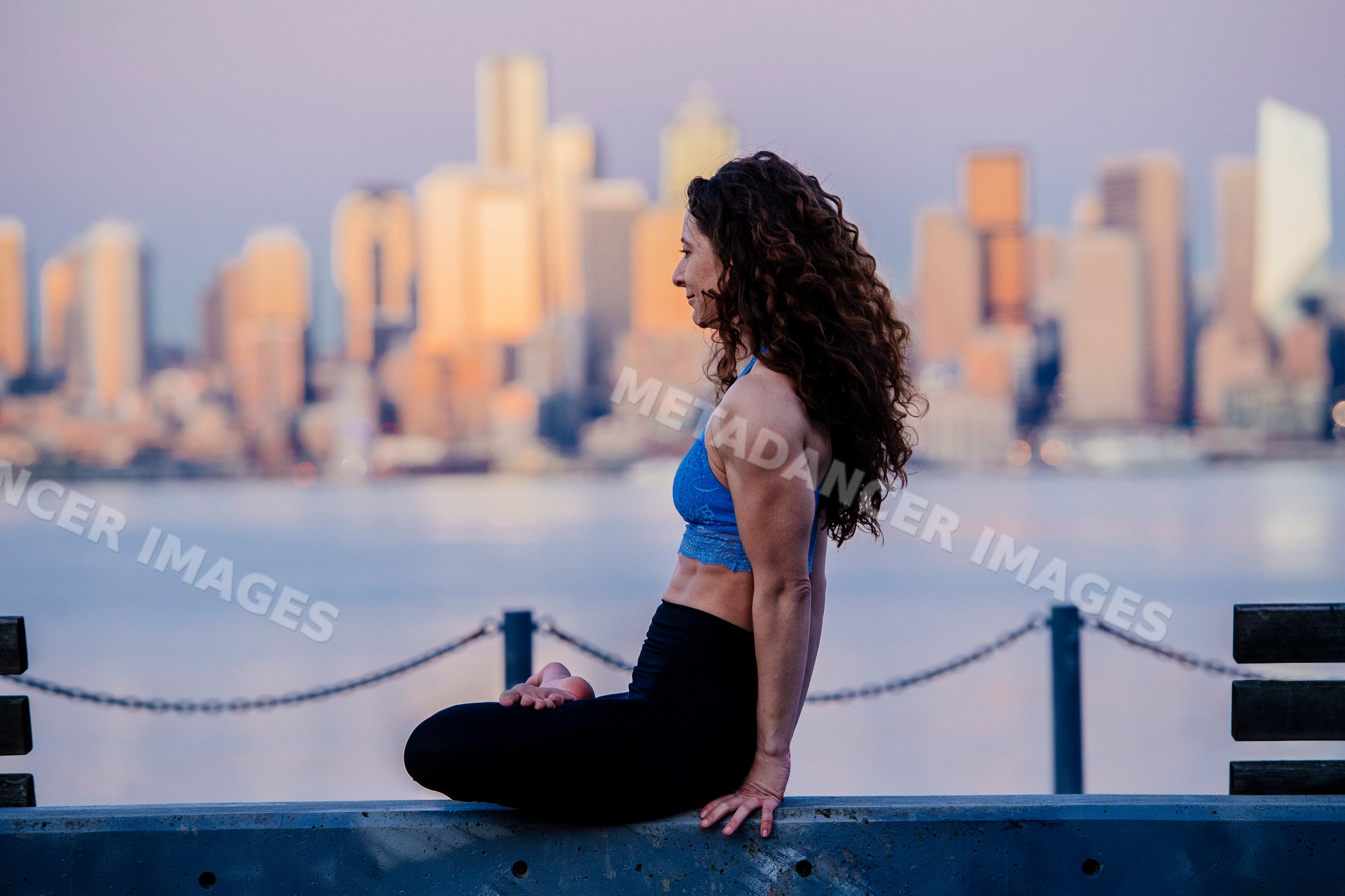 White woman practicing yoga by waterfront with Seattle skyline