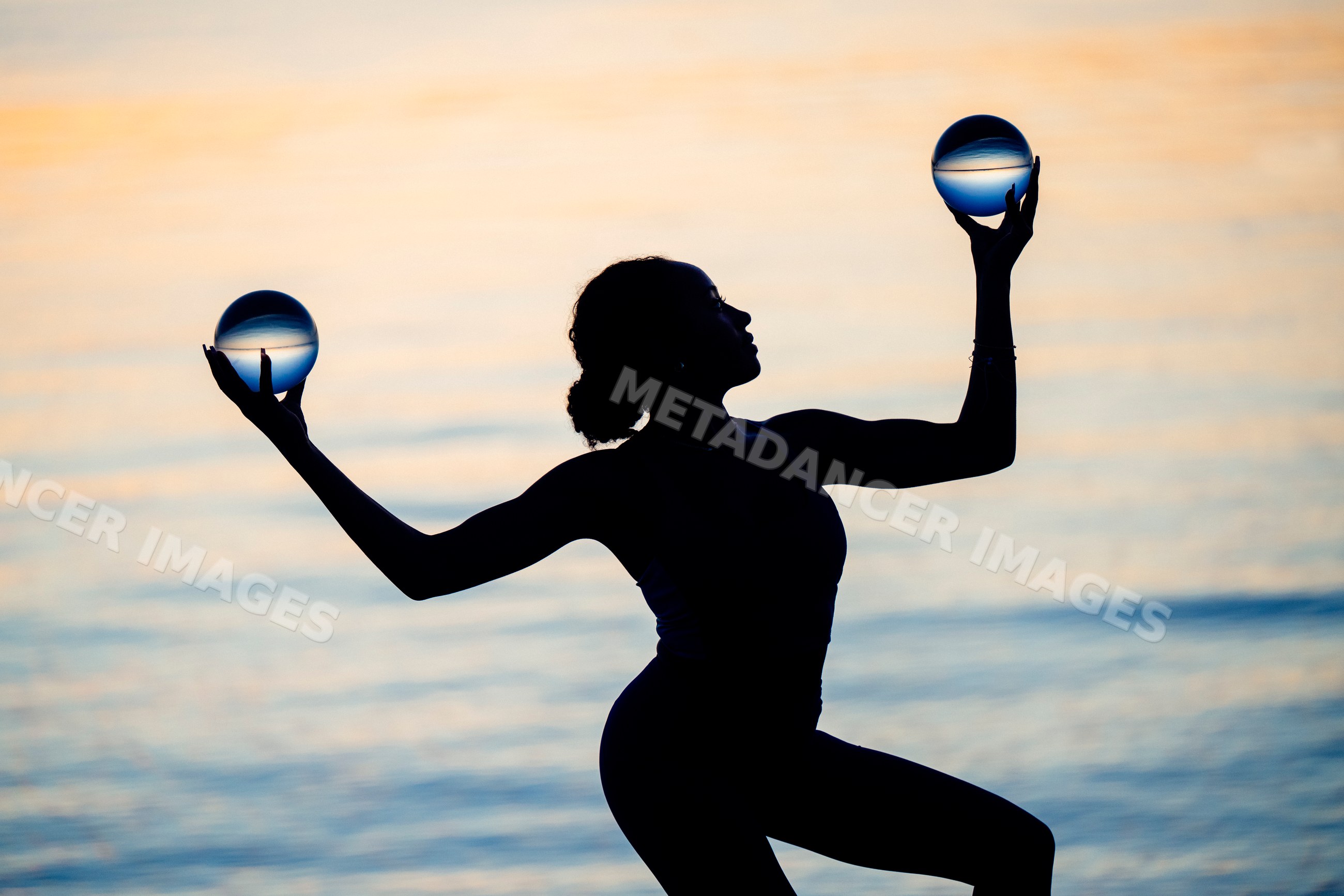 Hispanic woman silhouette balancing crystal spheres