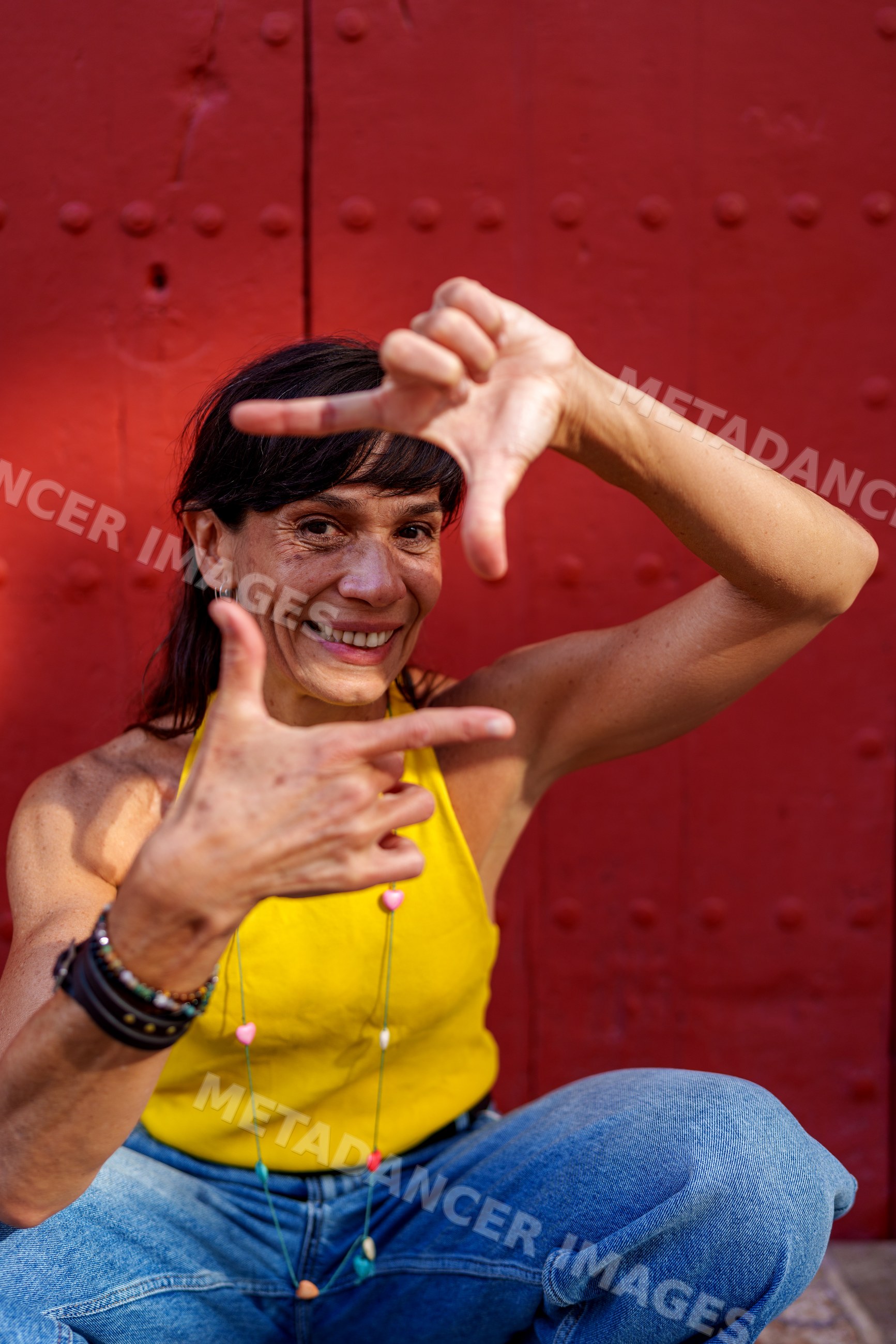 Hispanic woman smiling and framing with hands against red door