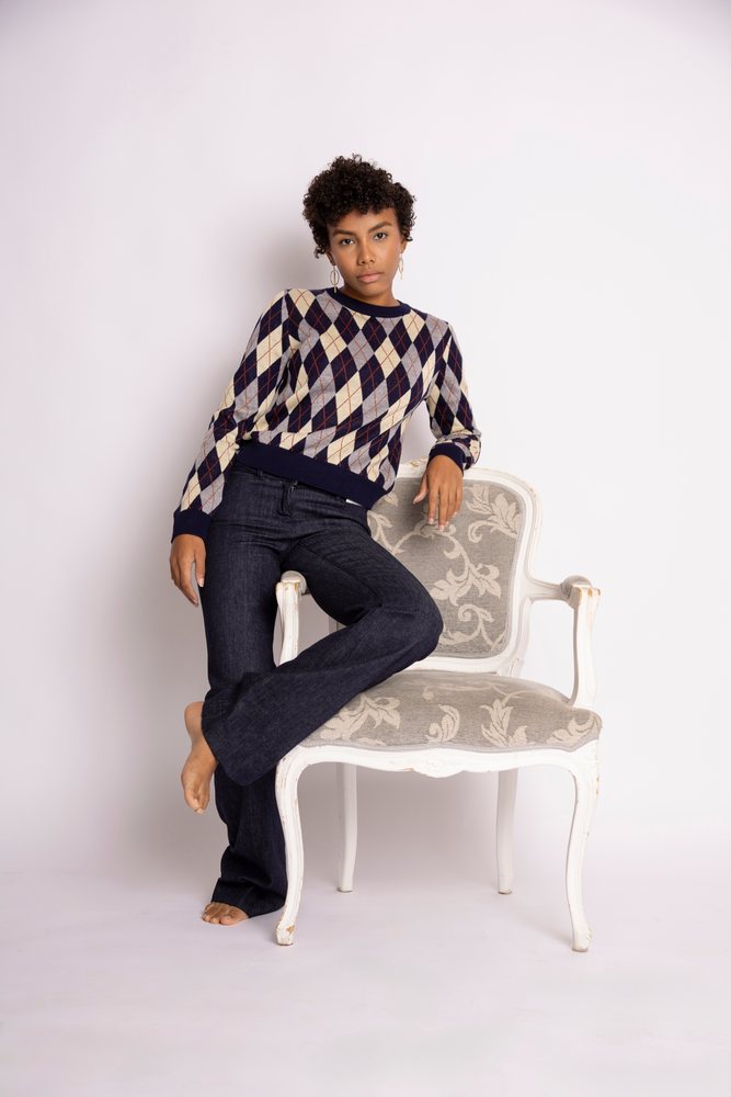 Hispanic woman posing barefoot next to white chair