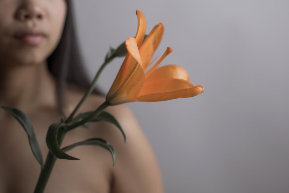 Orange lily flower held by Southeast Asian woman