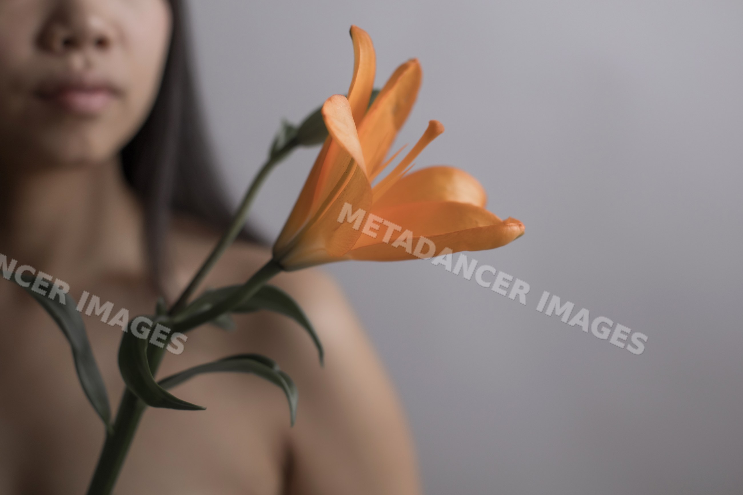 Orange lily flower held by Southeast Asian woman