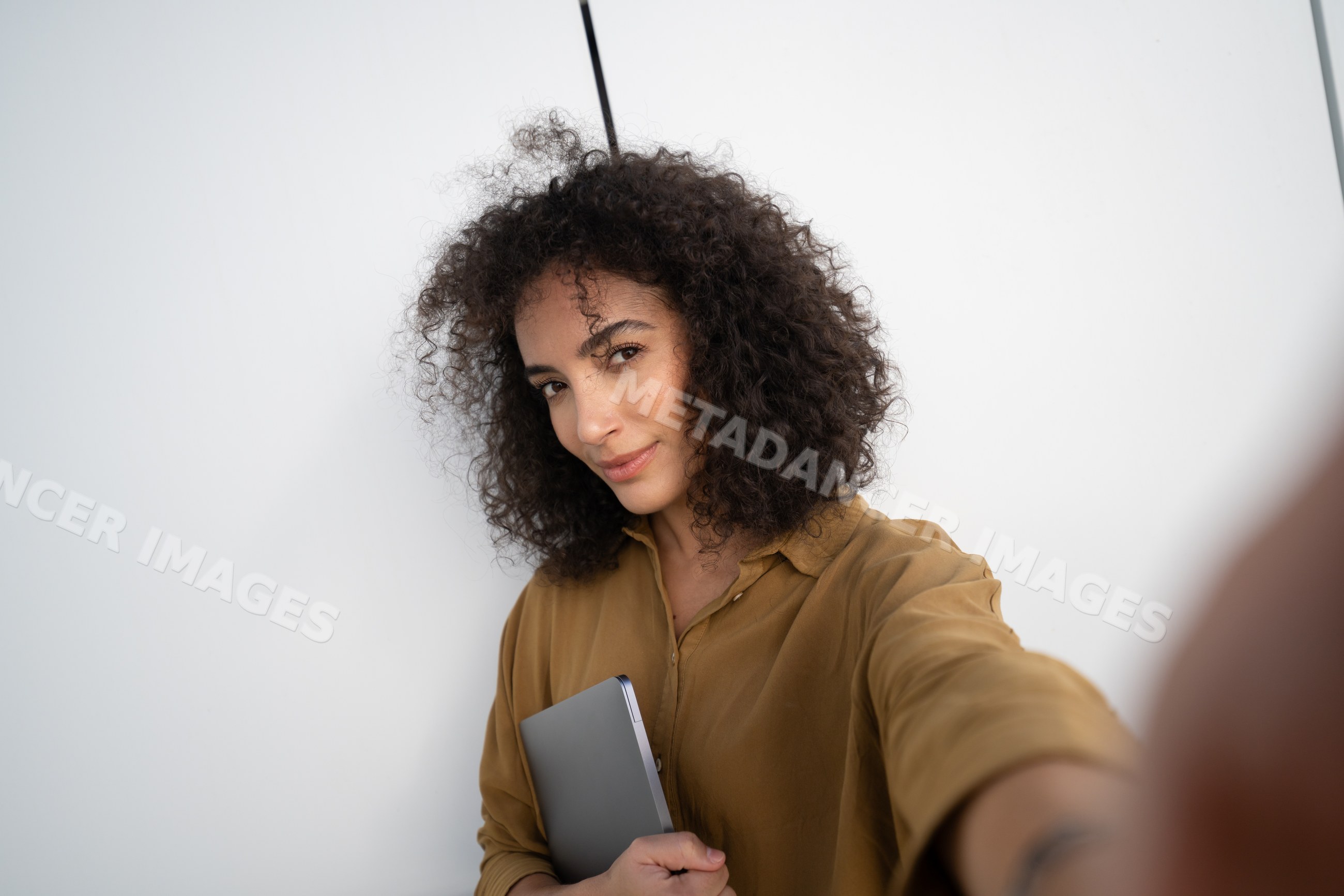 Woman holding a tablet and taking a selfie indoors
