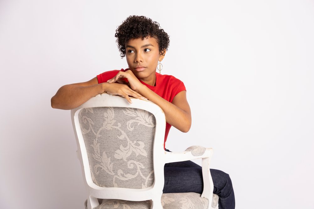 Young Hispanic woman sitting backwards on chair in red shirt