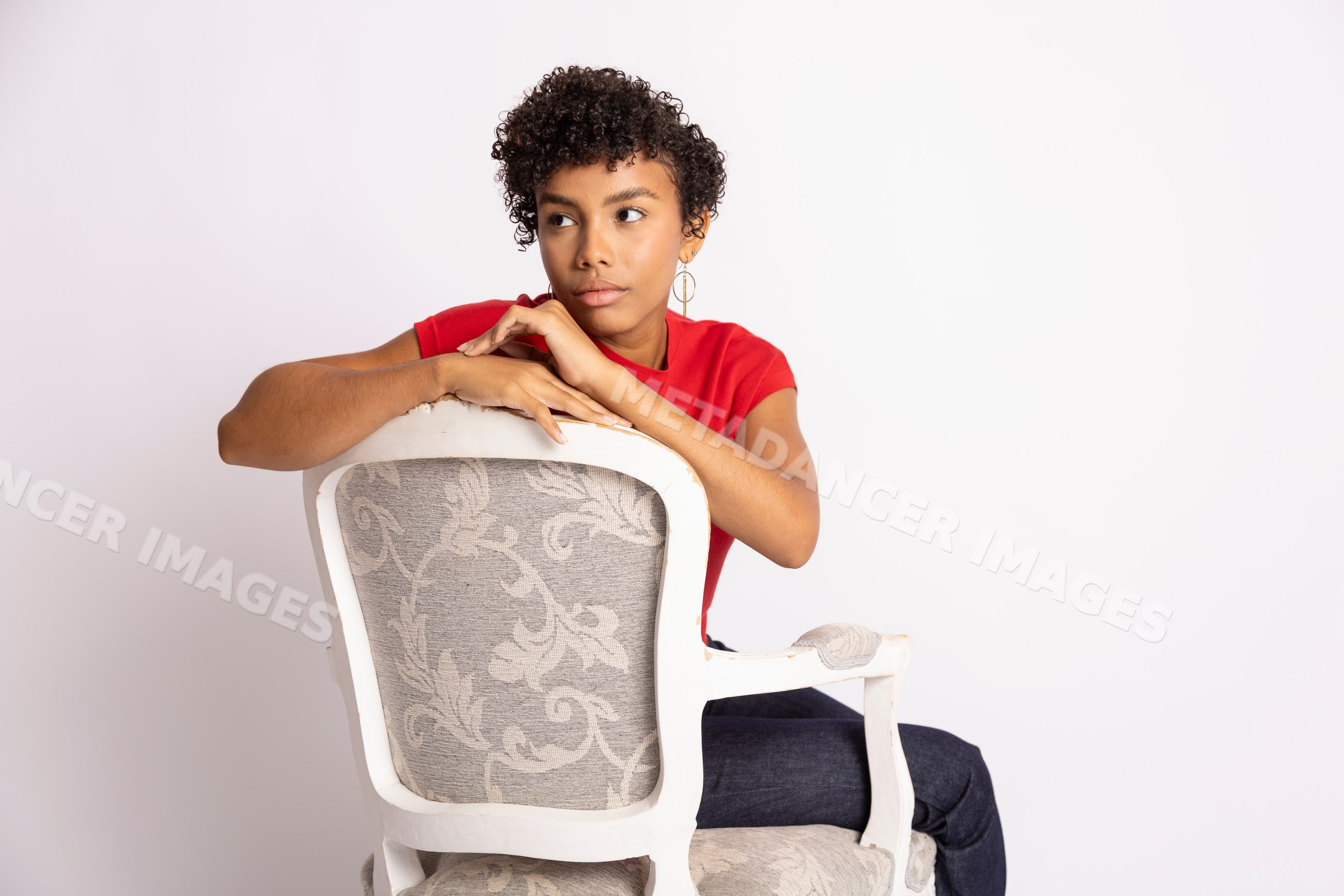 Young Hispanic woman sitting backwards on chair in red shirt