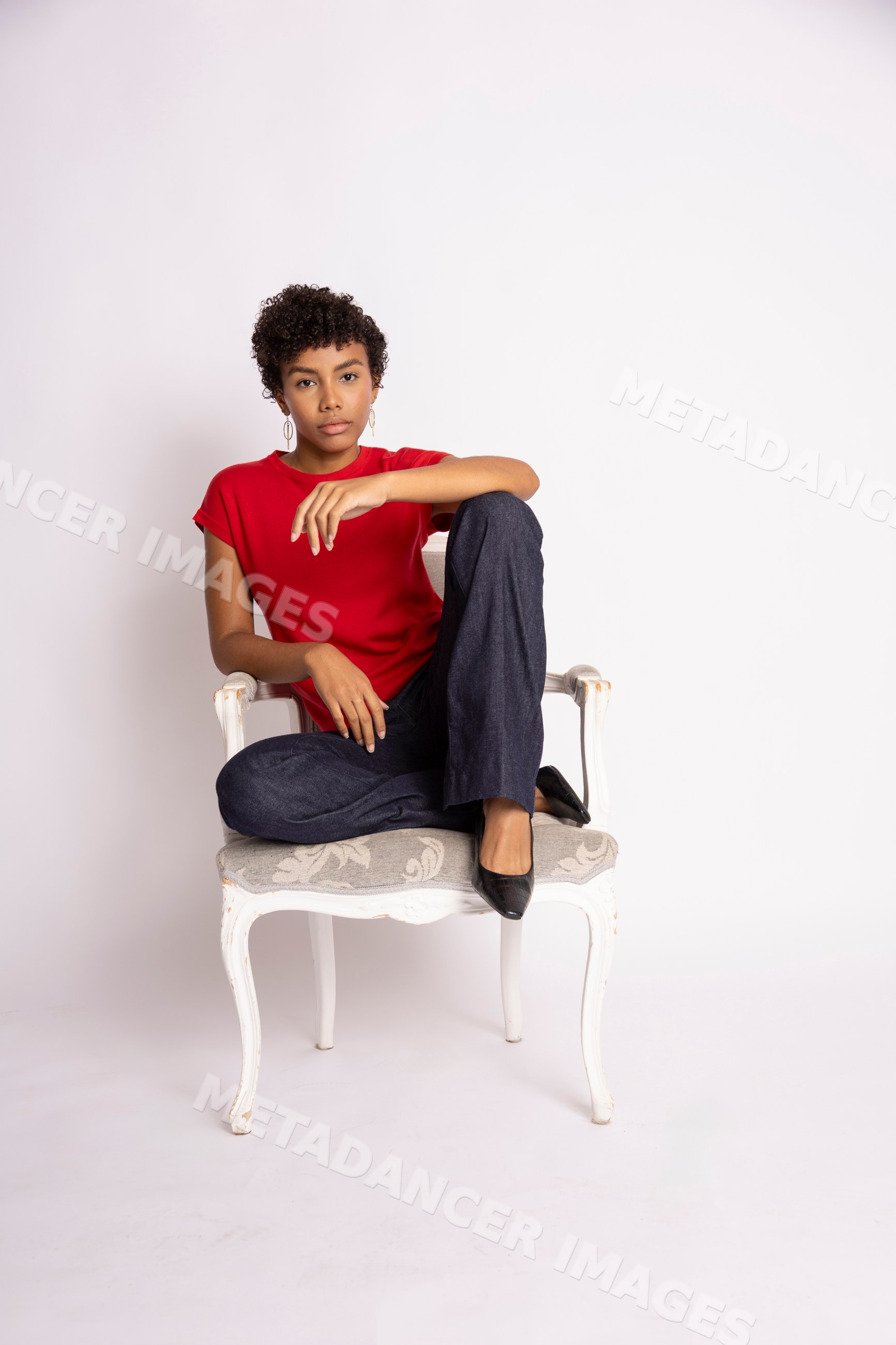 Hispanic woman sitting on a white chair wearing red shirt