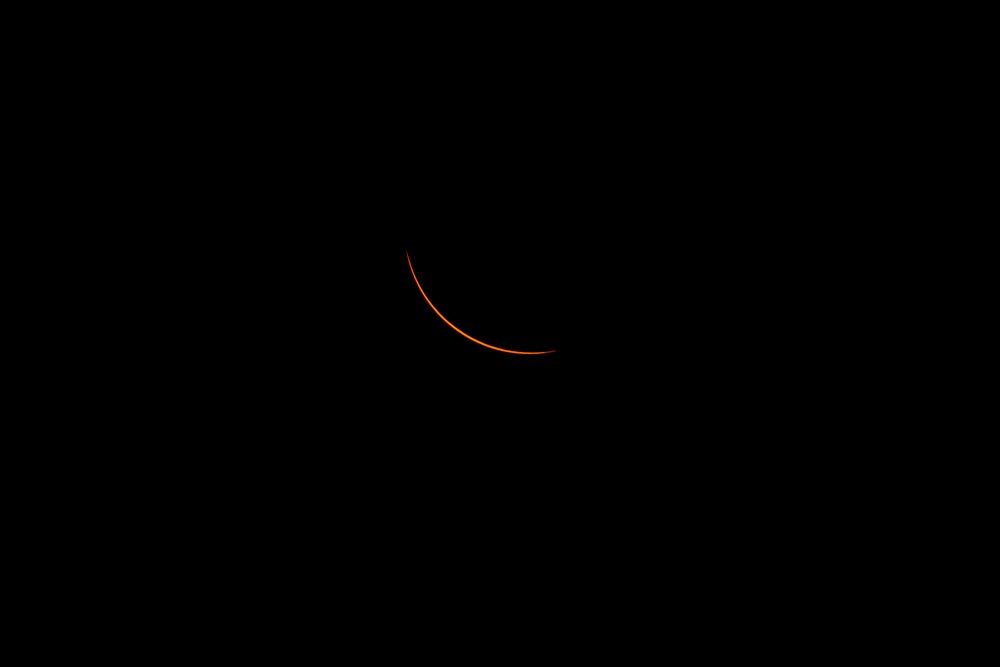 Solar eclipse showing crescent sun in dark sky