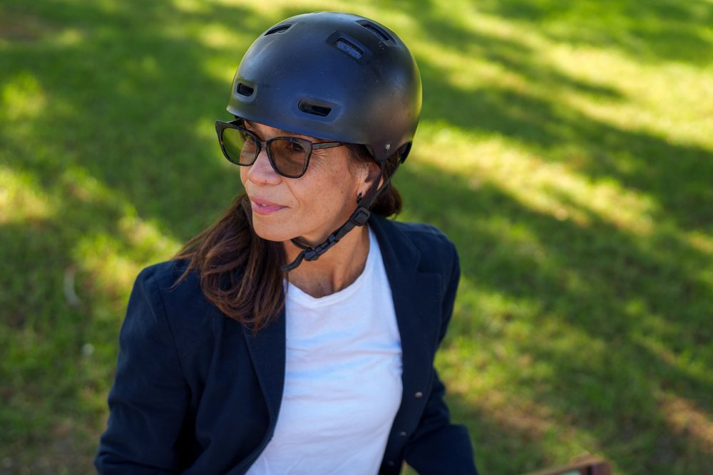 Hispanic woman wearing helmet sitting outdoors on grass