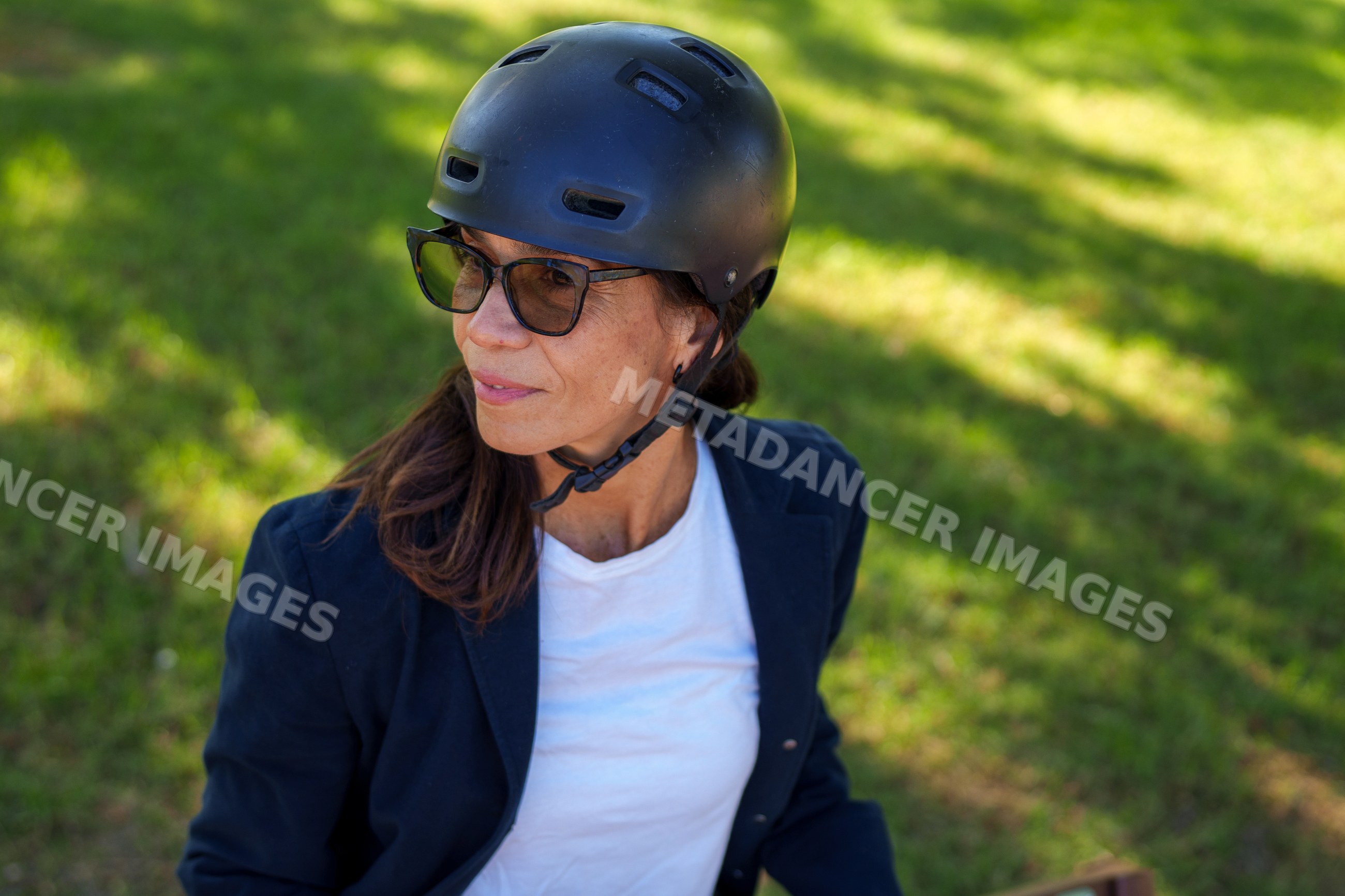 Hispanic woman wearing helmet sitting outdoors on grass