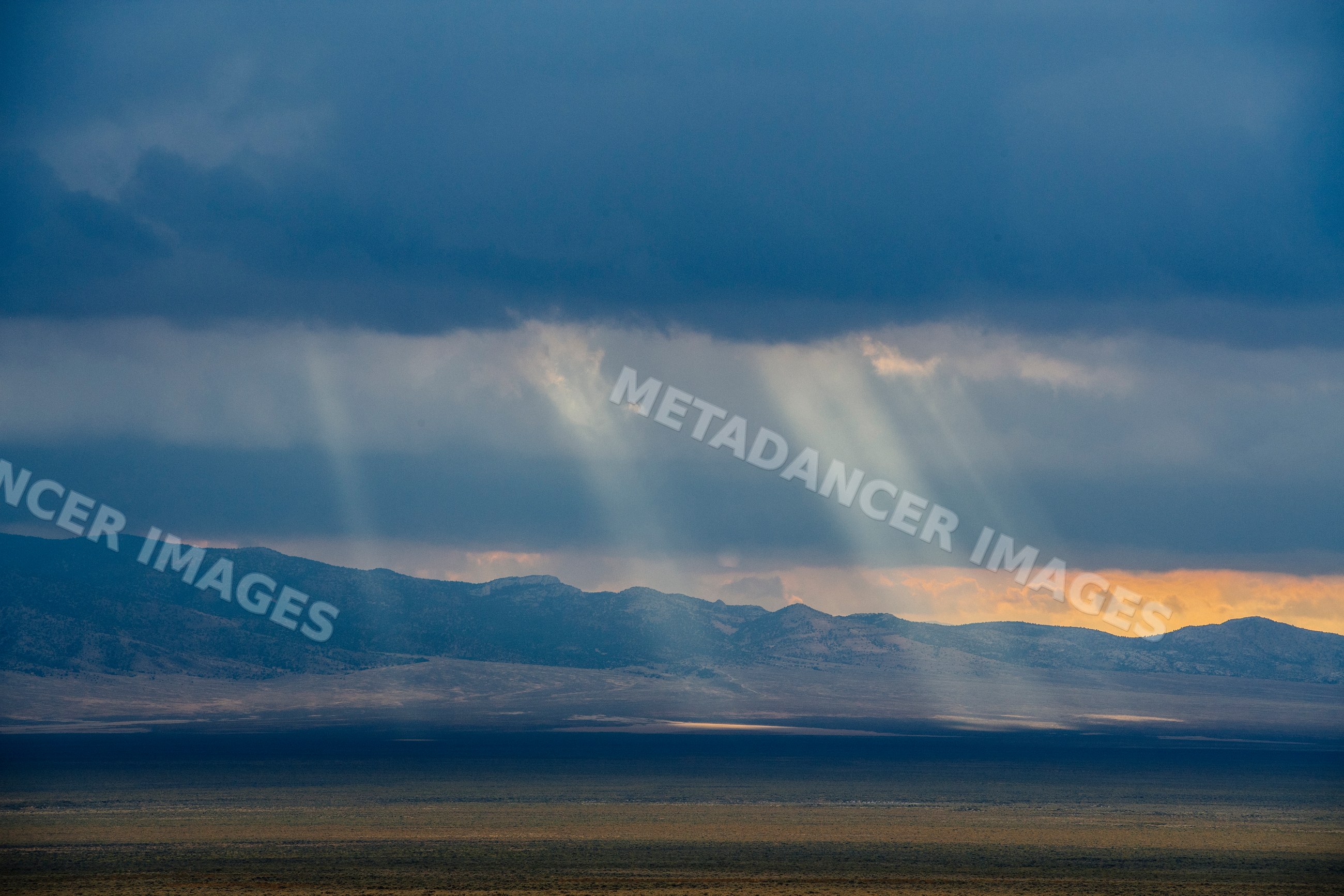 Sunlight beams shine on mountain range and desert