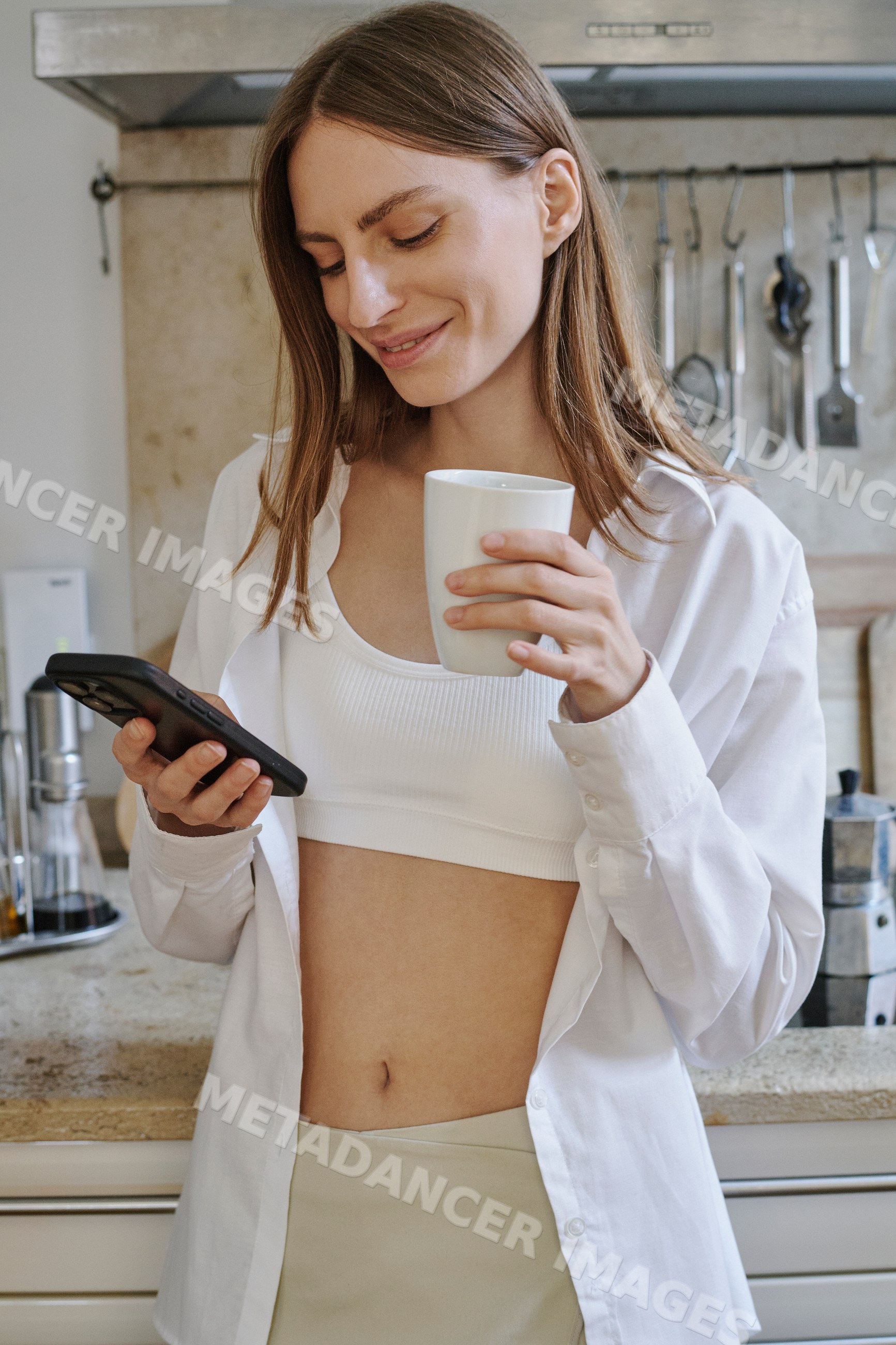 Young white woman drinks coffee and texts on smartphone