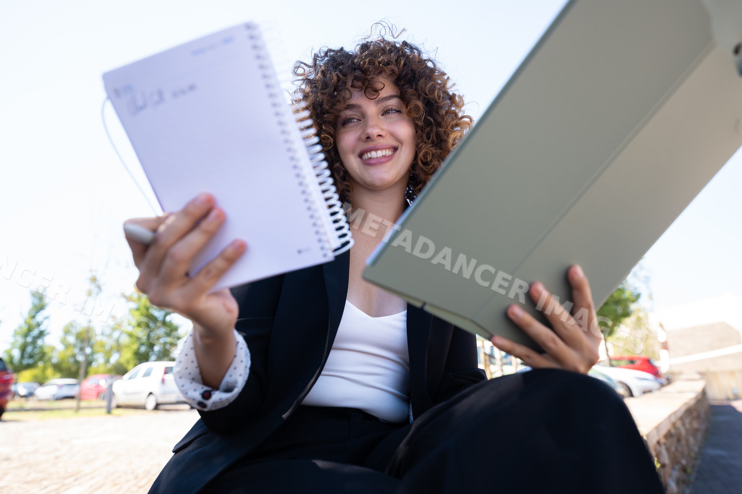 Businesswoman holding notebook and tablet outdoors