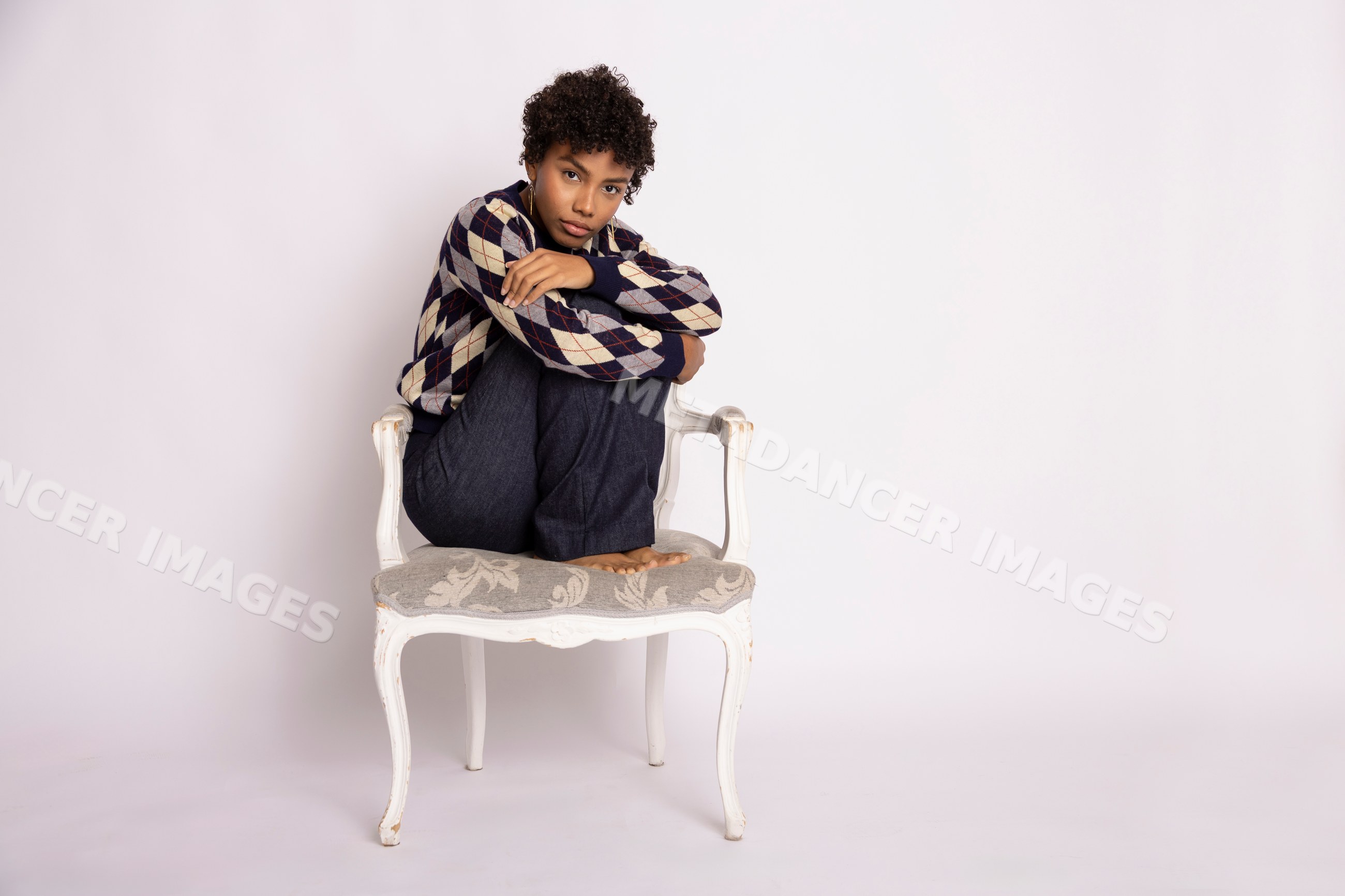 Hispanic woman sitting curled on chair